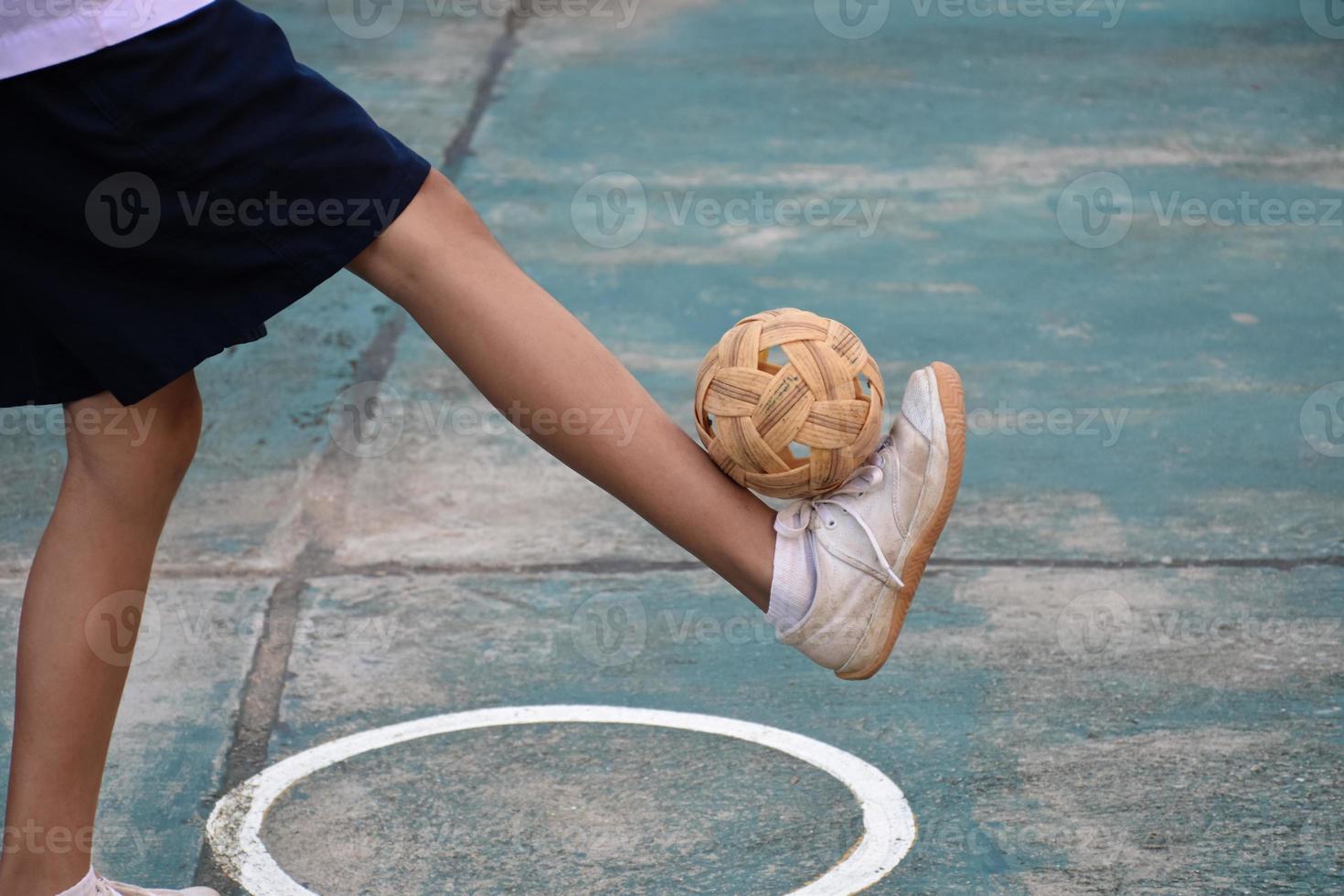 bola sepak takraw, esporte tradicional dos países do sudeste asiático, segurando na mão do jovem jogador sepak takraw feminino asiático na frente da rede antes de jogá-lo para outro jogador para chutar a rede. foto