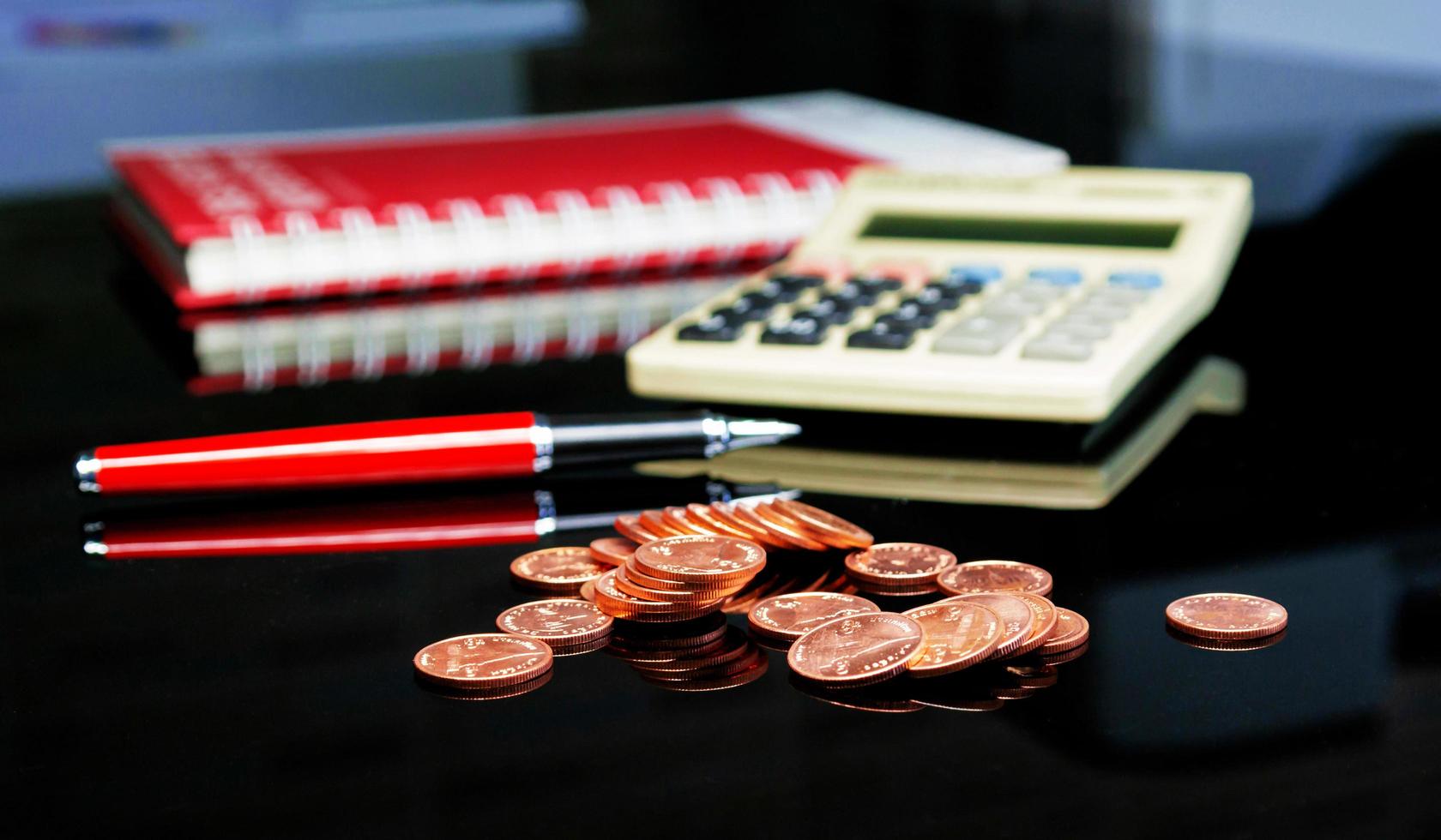 pilha de moedas na mesa com caneta e calcutor foto