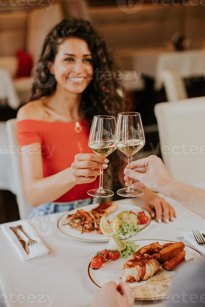 jovem casal almoçando com vinho branco no restaurante foto