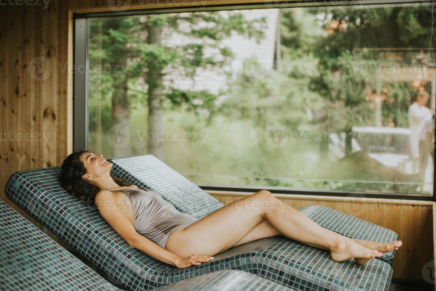 jovem relaxante na cama tepidarium no spa foto