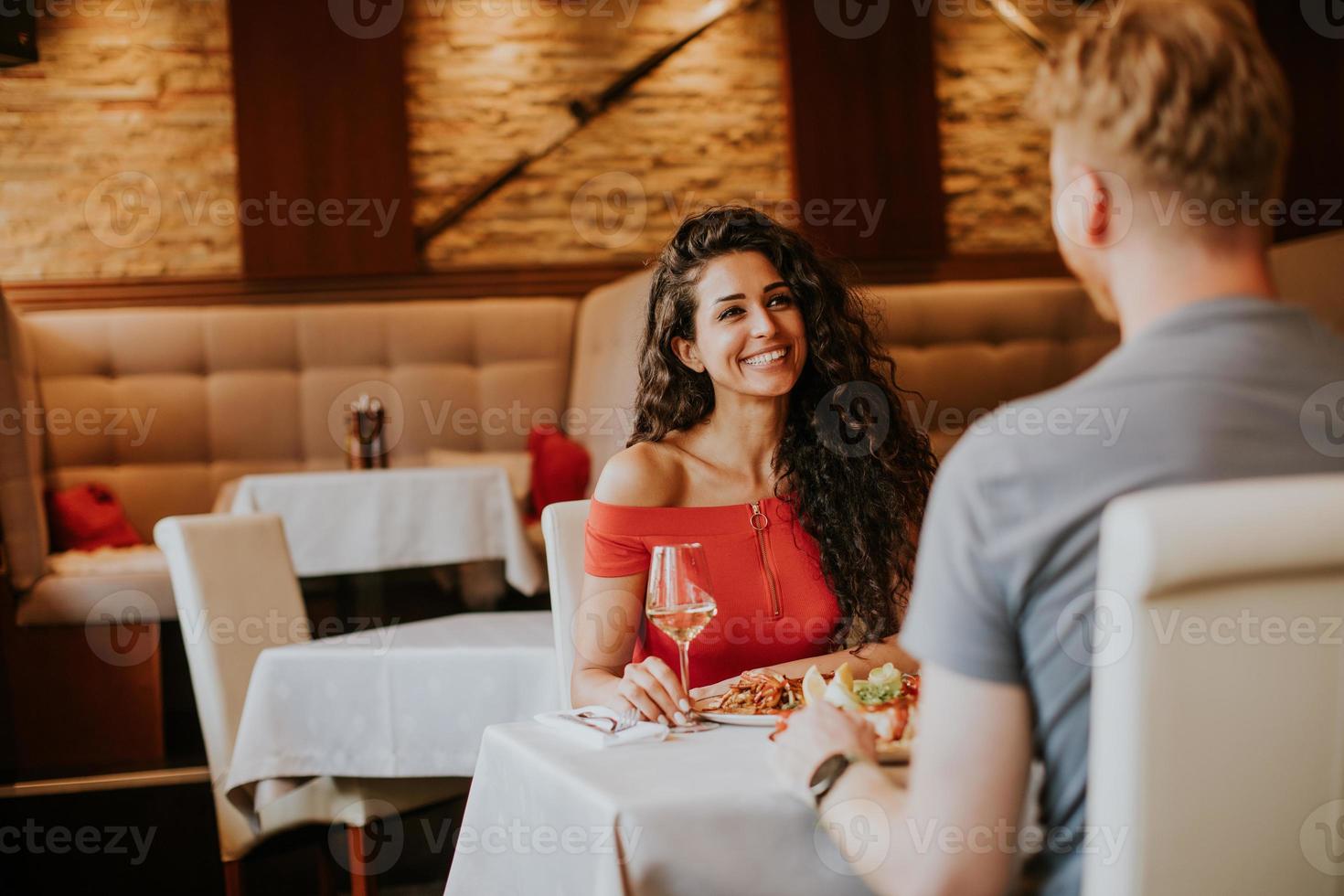 jovem casal almoçando com vinho branco no restaurante foto