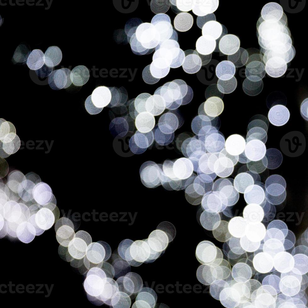 bokeh abstrato de luzes da cidade branca sobre fundo preto. desfocado e desfocado muitas luzes redondas foto