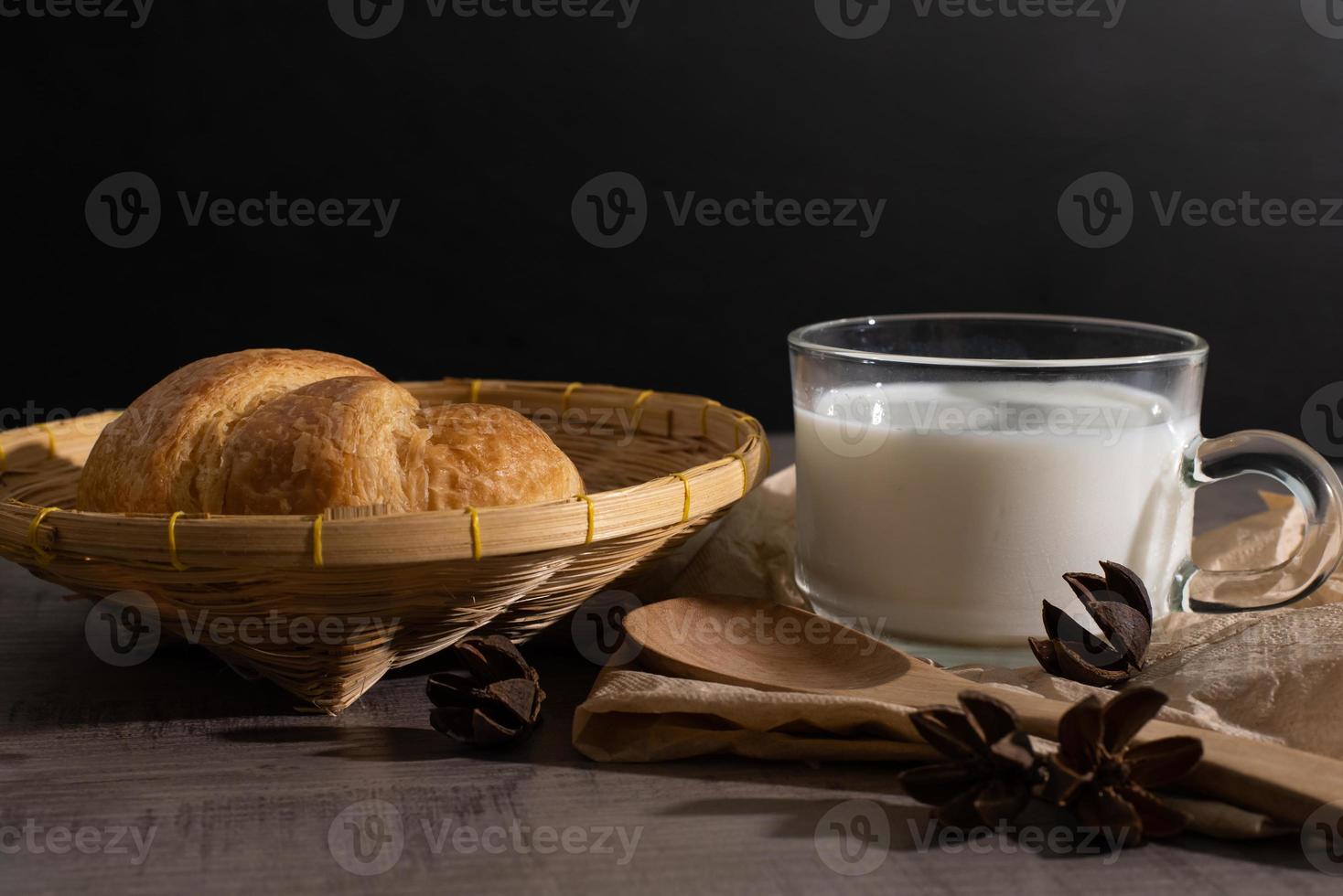 um conjunto de croissant e xícara de leite na mesa de madeira foto