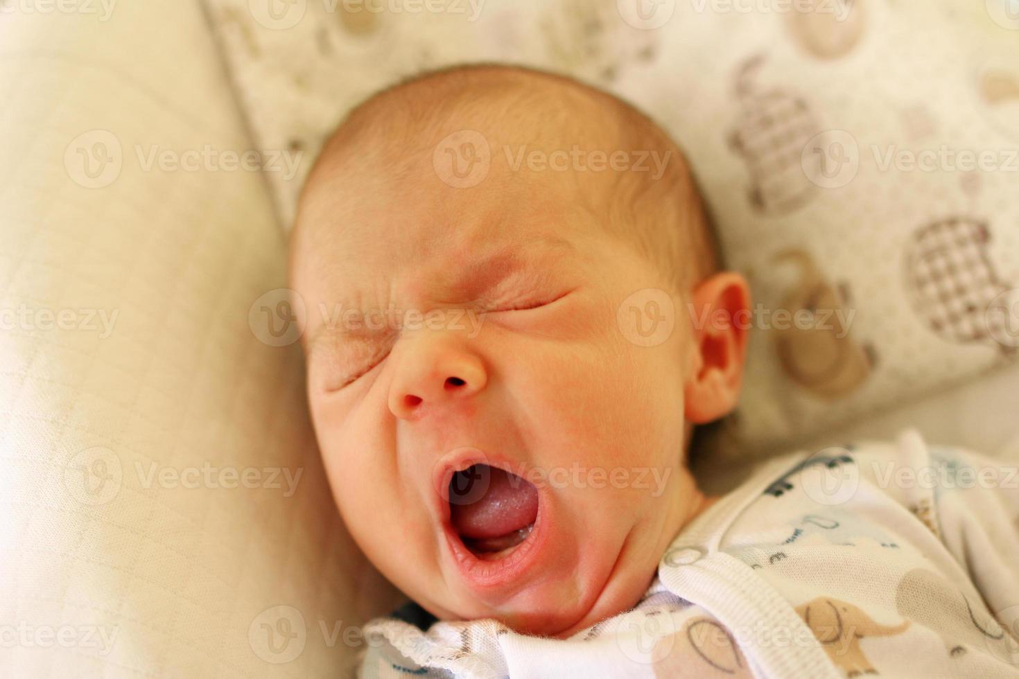 lindo bebê recém-nascido está bocejando antes de ir para a cama. foto