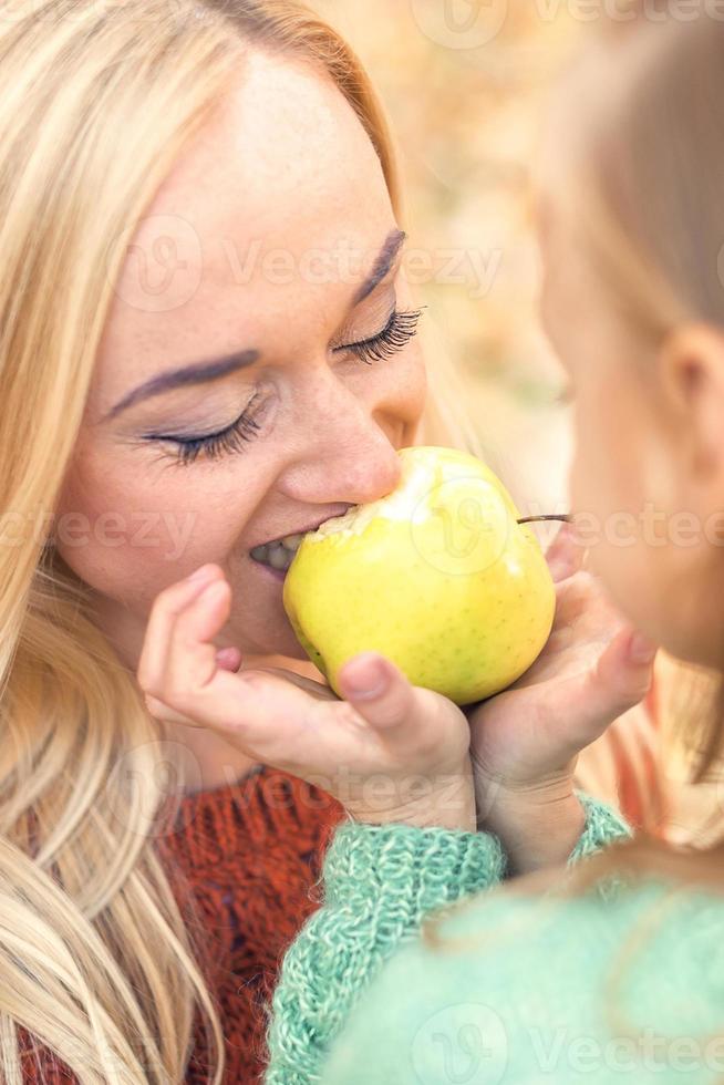 menina com mãe comendo maçã foto