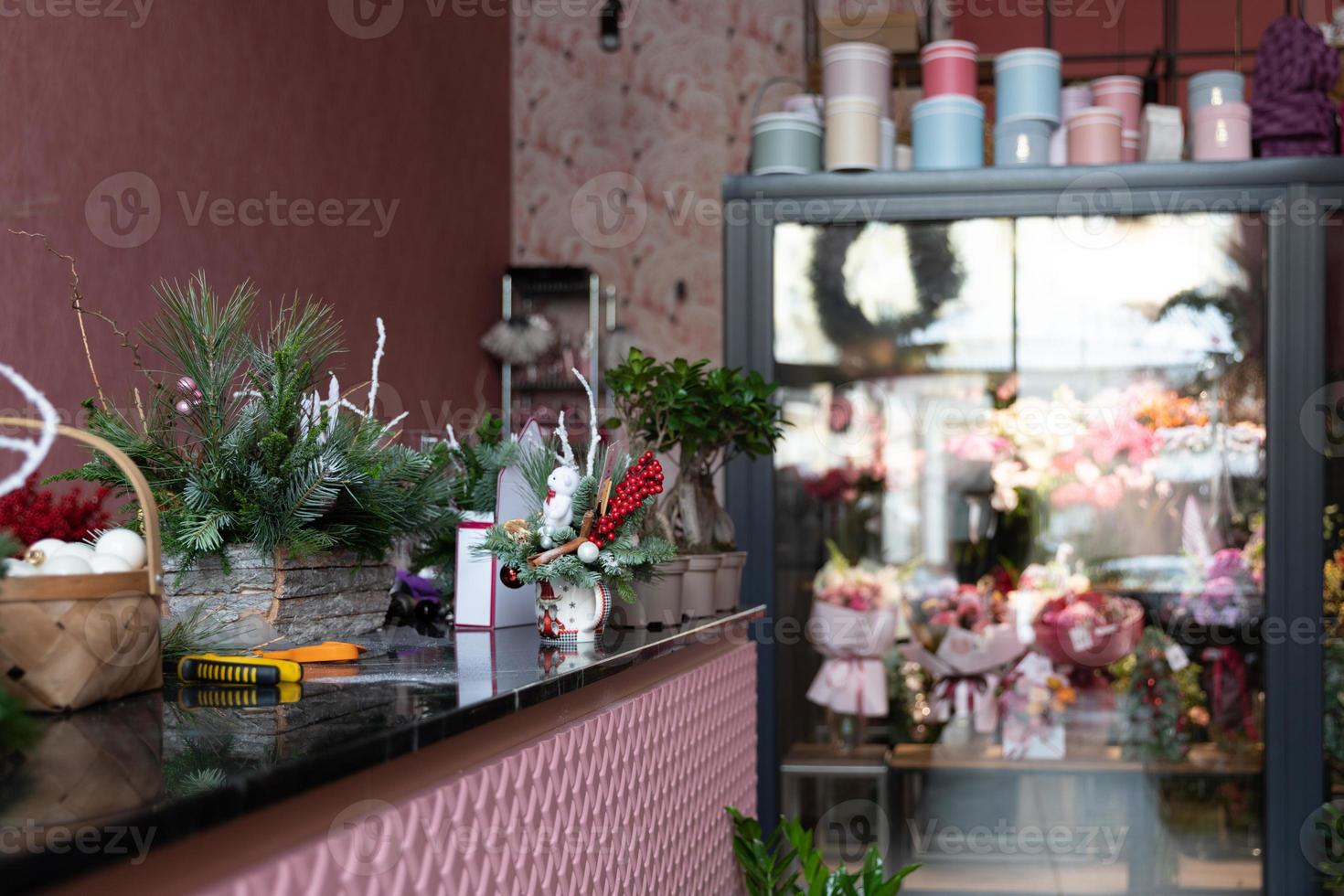 o interior de uma loja elegante que vende flores com um arranjo de árvore de natal feito de agulhas de pinheiro natural no balcão em primeiro plano foto