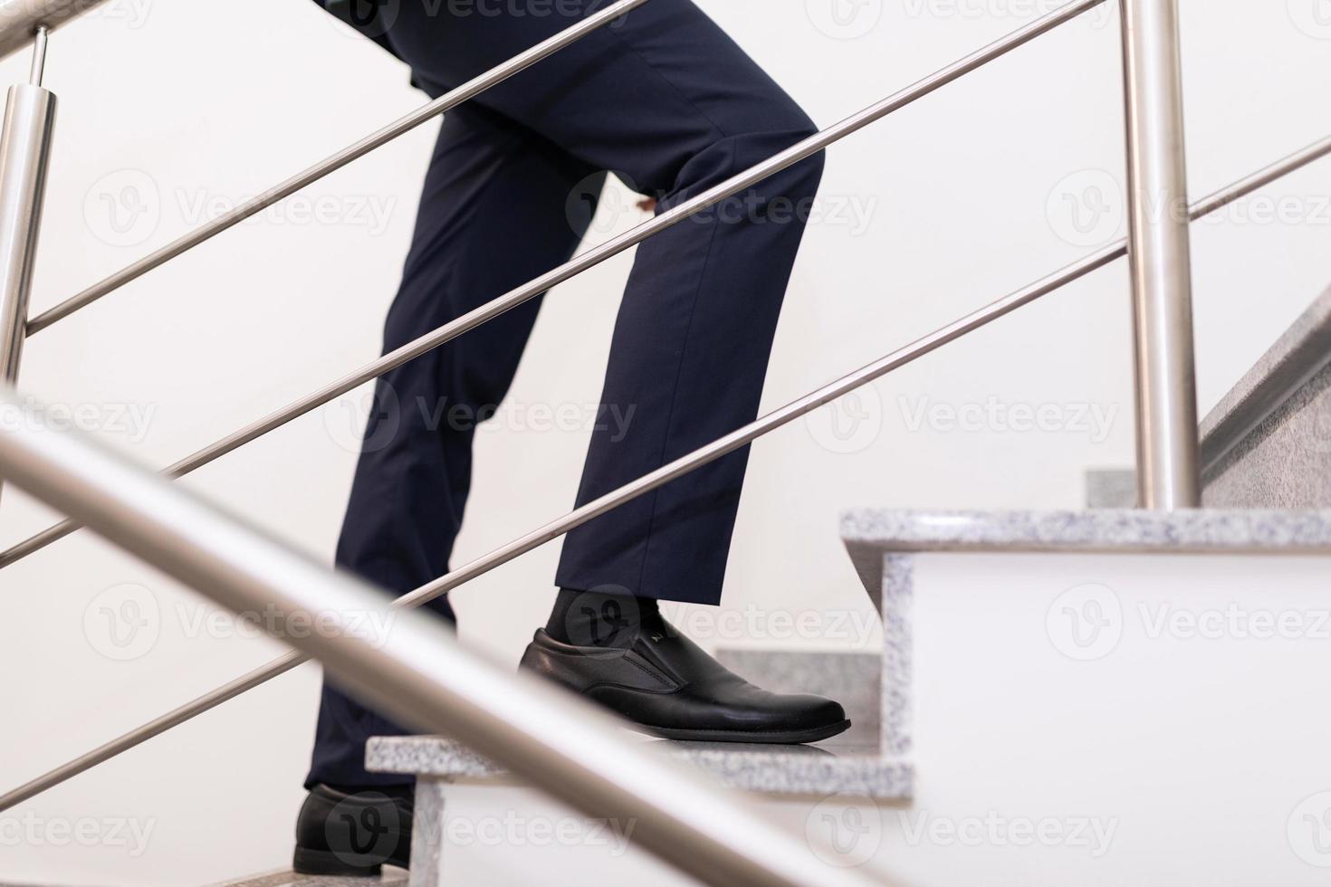 close-up das pernas de um empresário subindo as escadas, o conceito de um negócio de sucesso e crescimento de carreira foto