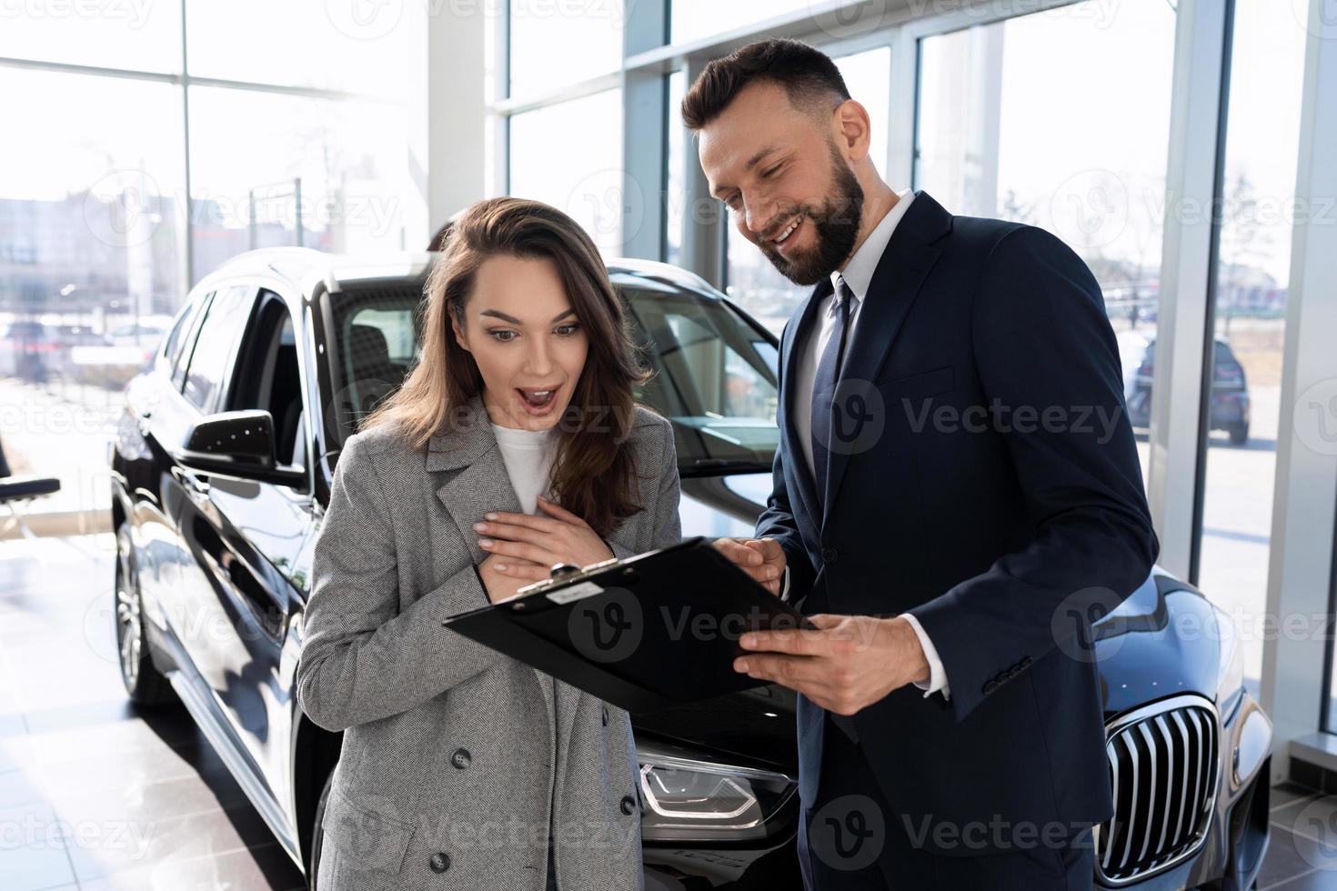 jovem versada em polo de seguro automóvel juntamente com consultor em concessionária de automóveis foto