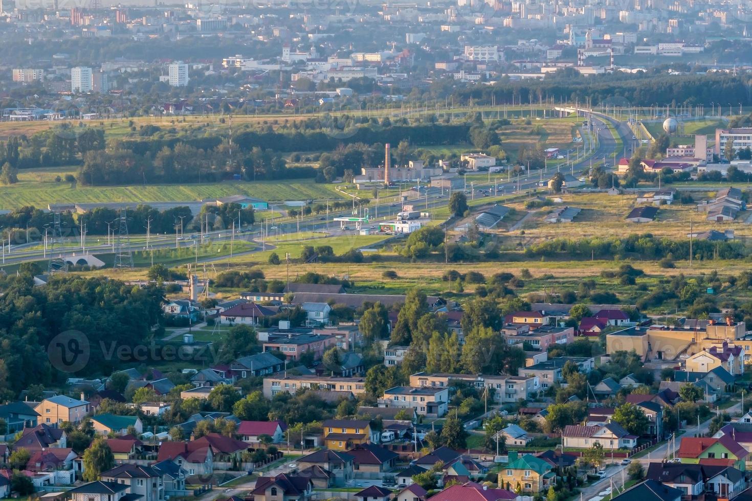 vista panorâmica aérea da aldeia verde com homestads, casas, celeiros e estrada de cascalho na floresta foto