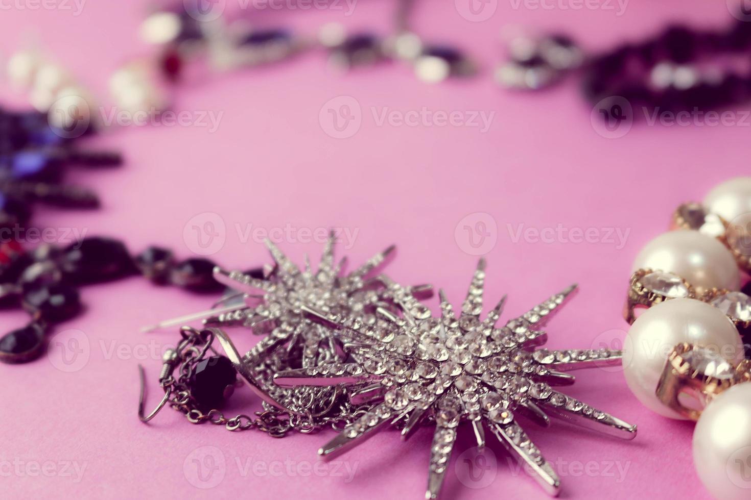 belas jóias brilhantes preciosas na moda conjunto de jóias glamourosas, colar, brincos, anéis, correntes, broches com pérolas e diamantes em um fundo rosa roxo. configuração plana, vista superior, local de cópia foto