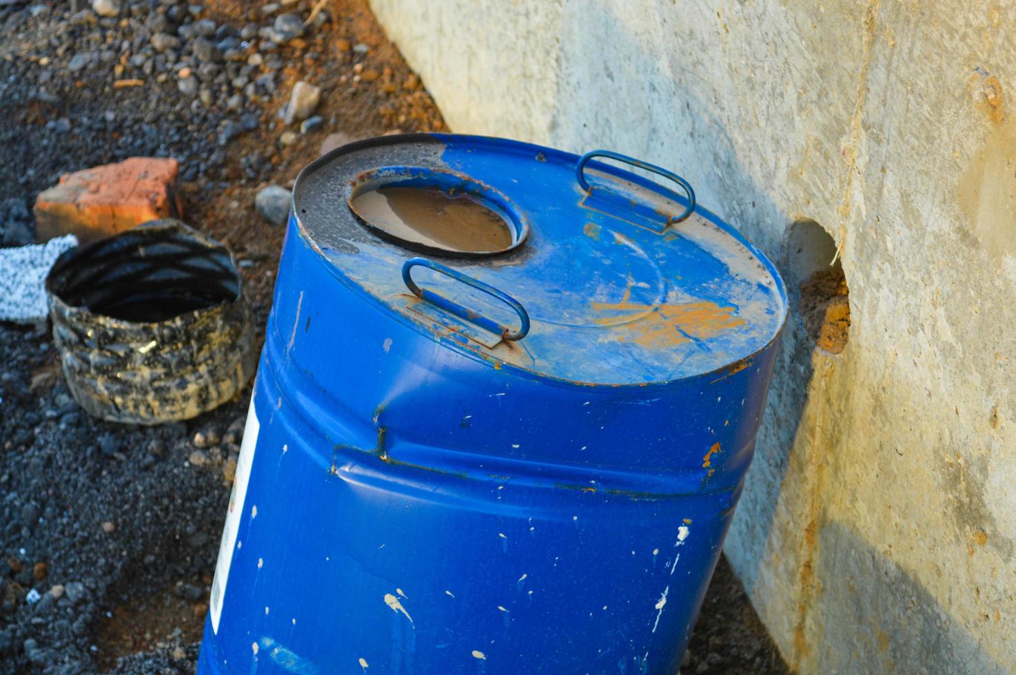 um barril azul brilhante fica na estrada. um líquido inflamável é derramado dentro do barril. um barril com um buraco dentro fica no centro da cidade em um canteiro de obras foto