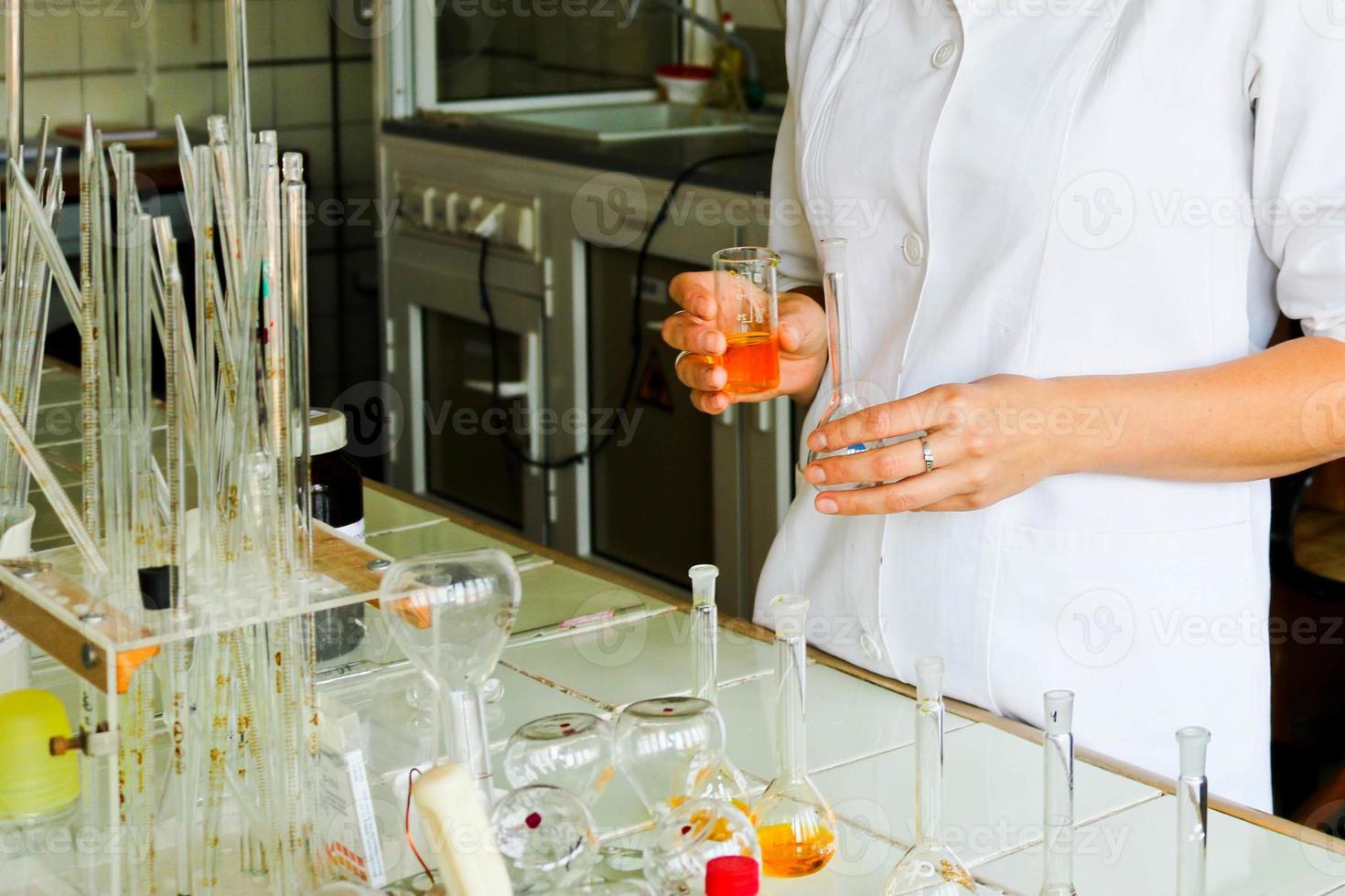 uma assistente de laboratório feminina, médica, química, trabalha com frascos, tubos de ensaio, faz soluções, medicamentos, mistura os ingredientes no laboratório. assistente de laboratório realiza a pesquisa foto