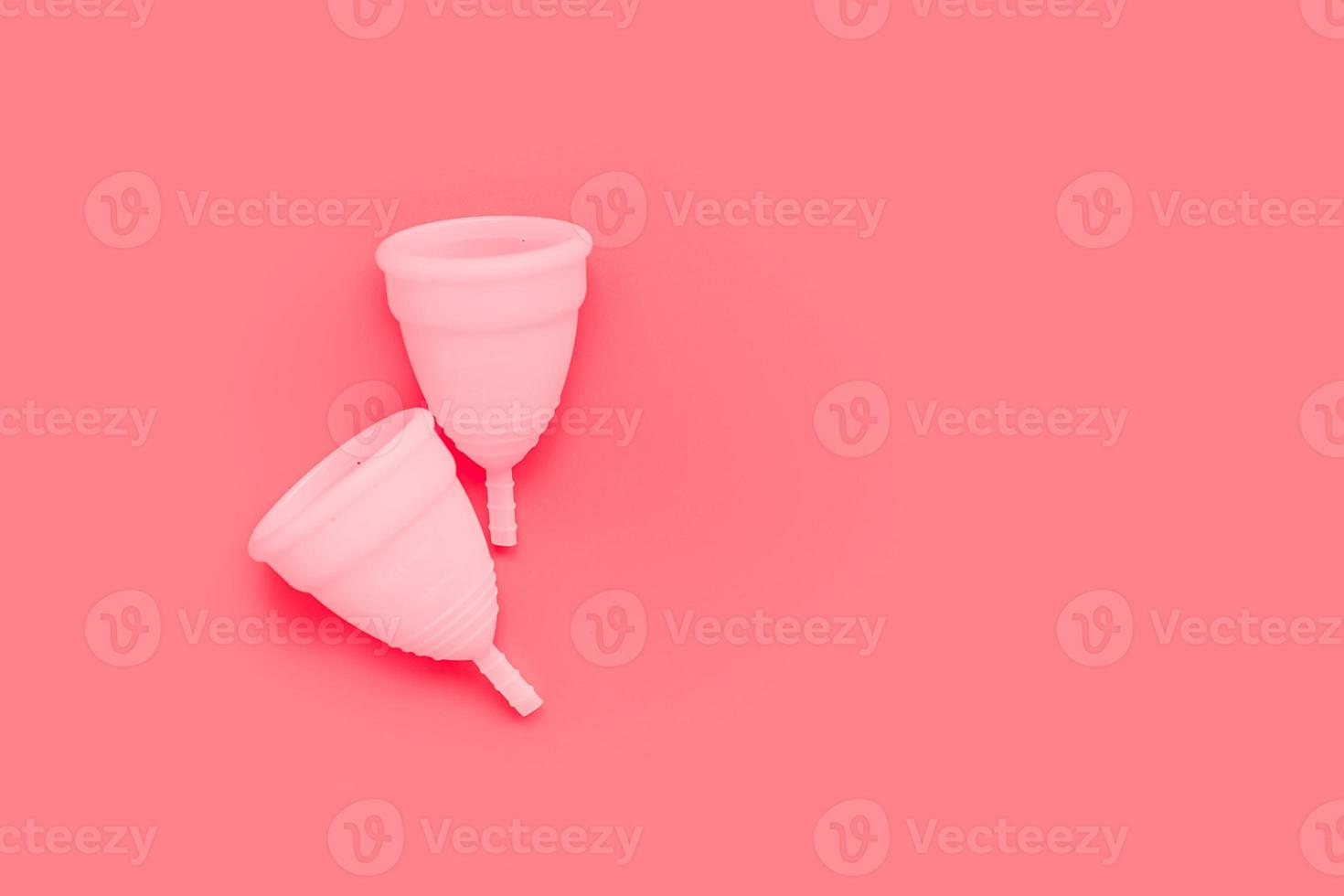 copo menstrual rosa na cor de fundo, produtos do período de higiene íntima feminina, vista superior foto