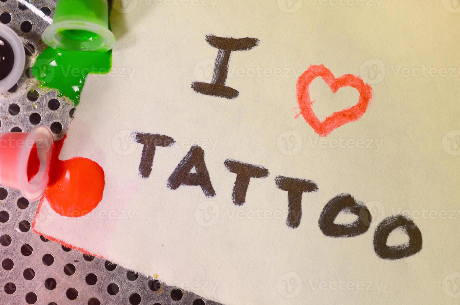 eu amo tatuagem. o texto está escrito em uma pequena folha de papel ao lado das tampas viradas com tinta de tatuagem colorida foto