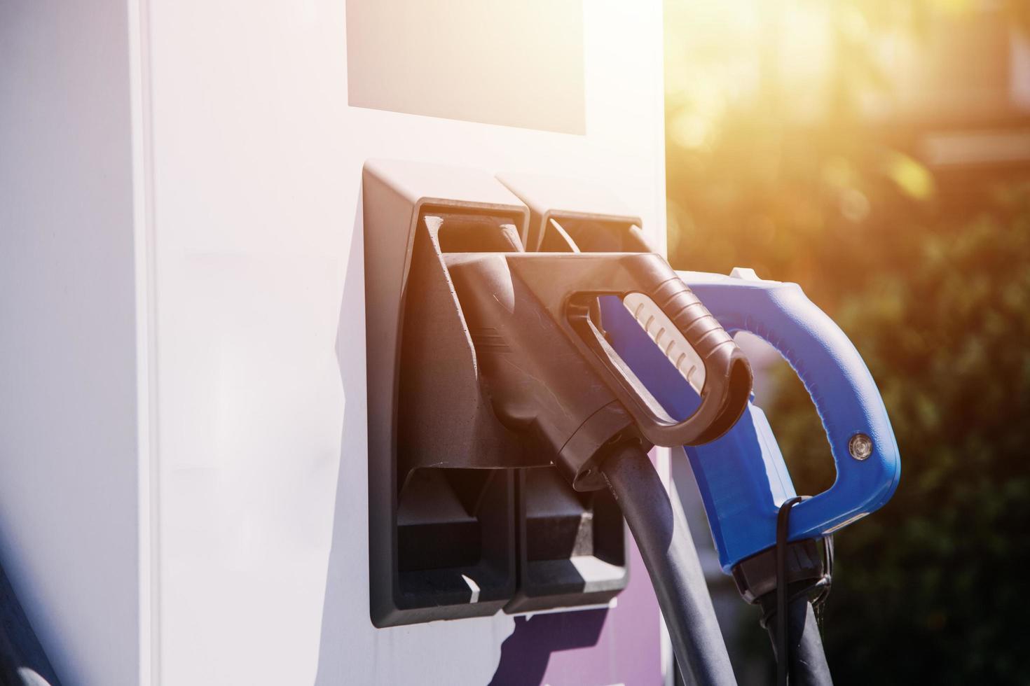 mão conectando um carregador em uma tomada de carro elétrico. carro elétrico ou ev está carregando na estação foto