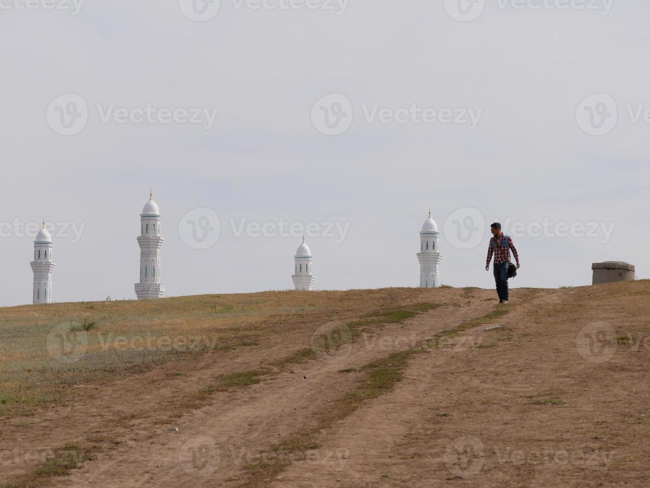 homem subindo uma colina em nur-sultan, cazaquistão, com uma mesquita ao fundo foto