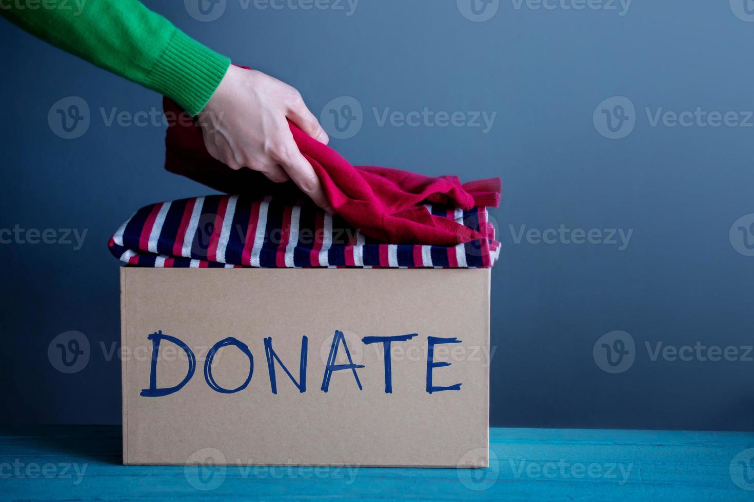 conceito de doação. mulher preparando suas roupas velhas usadas em uma caixa de doação foto