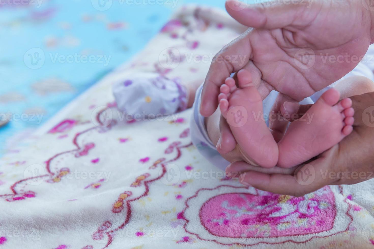 mãos de pais segurando os pés de menina bebê recém-nascido pequeno. foto