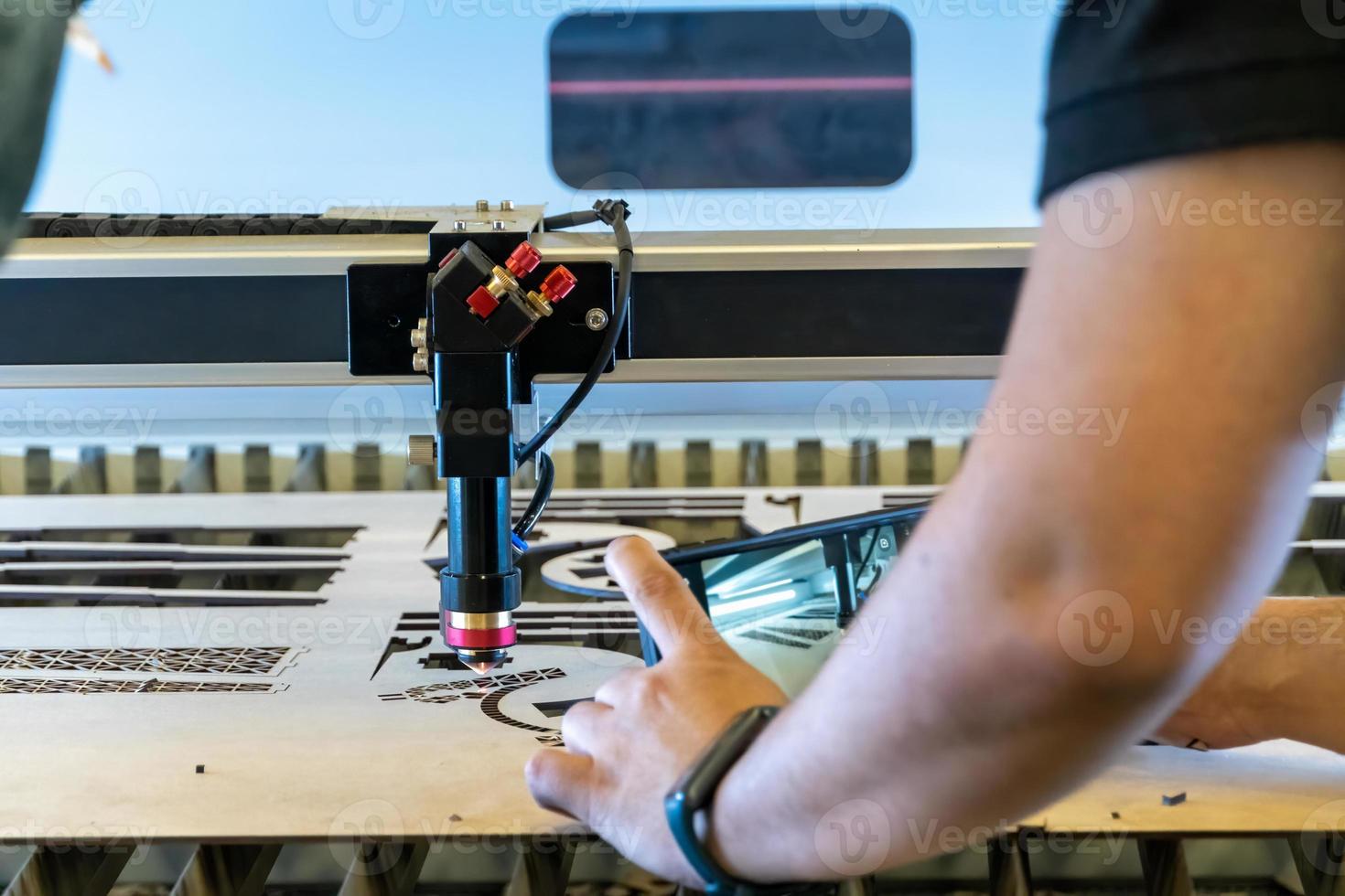 máquina de corte a laser, cortando folhas de madeira, enquanto um homem grava o processo, méxico foto