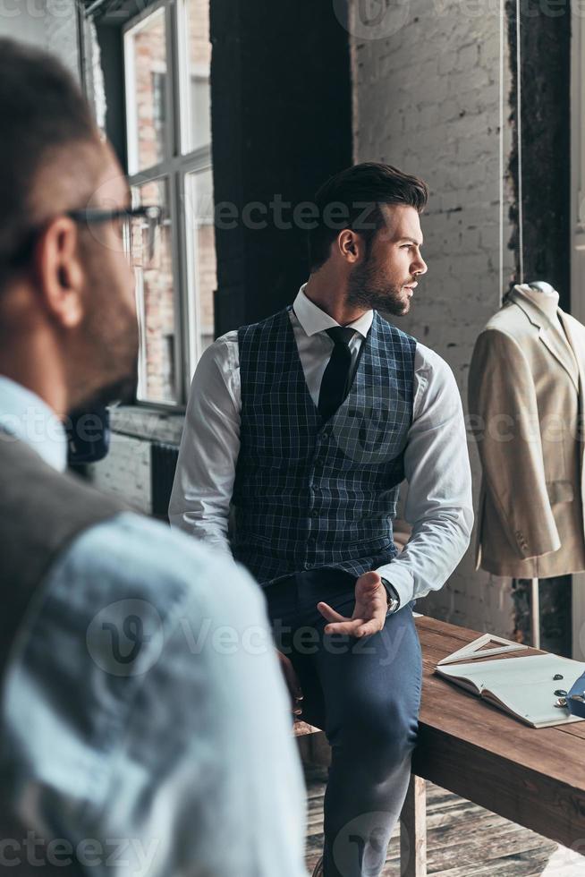 cada detalhe deve ser perfeito. dois jovens elegantes discutindo enquanto passavam o tempo na oficina foto