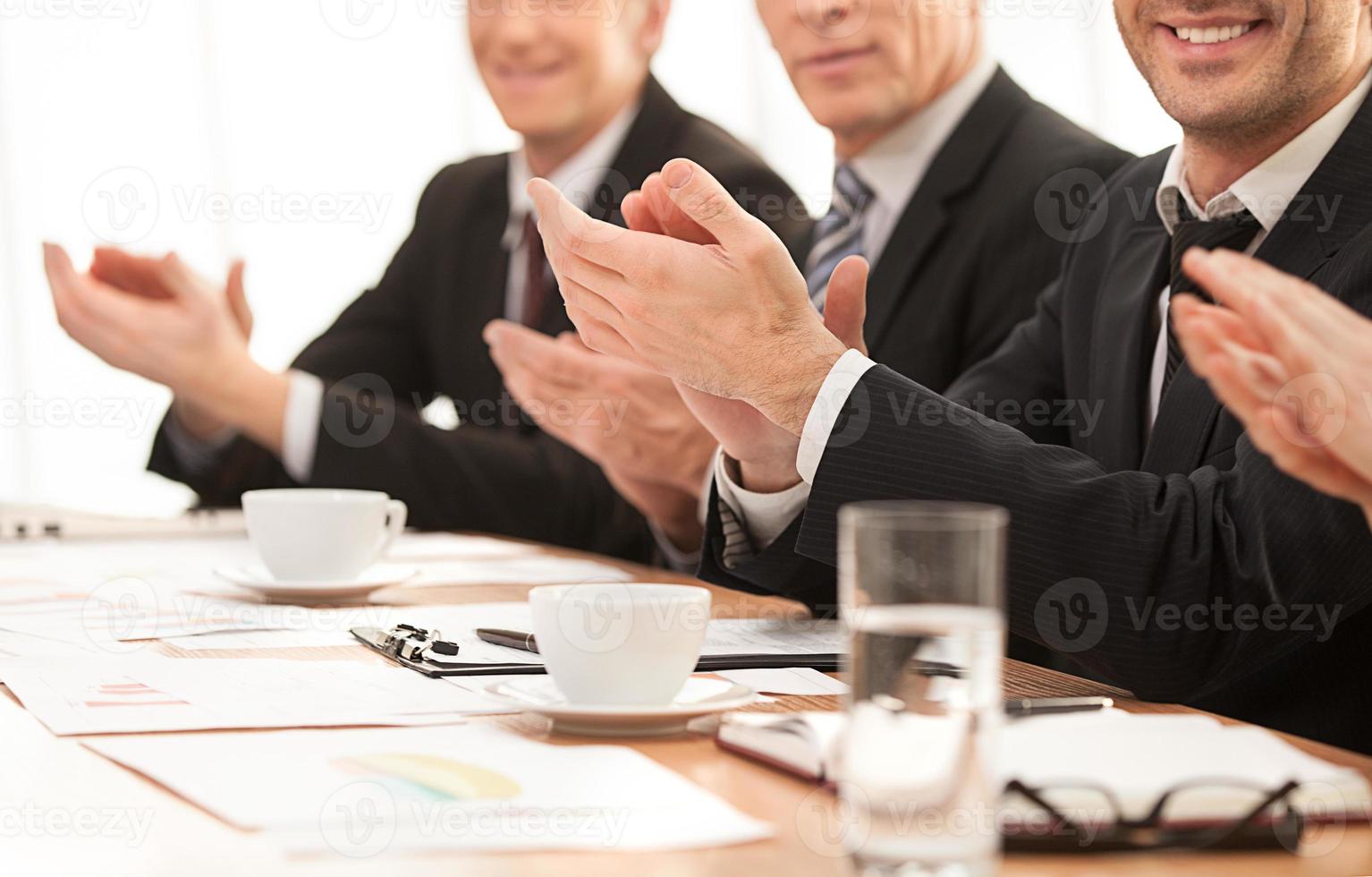 sucesso. imagem recortada de pessoas em trajes formais sentados juntos à mesa e aplaudindo você foto