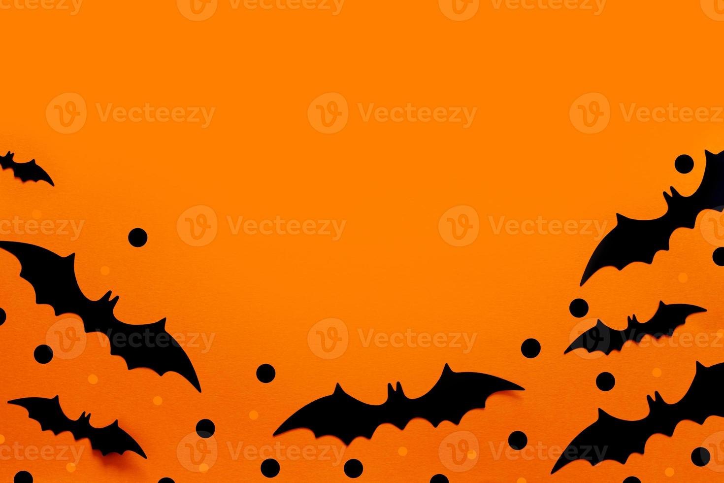 composição plana leiga de halloween de morcegos de papel preto fand abóboras em fundo laranja. conceito de dia das bruxas. foto