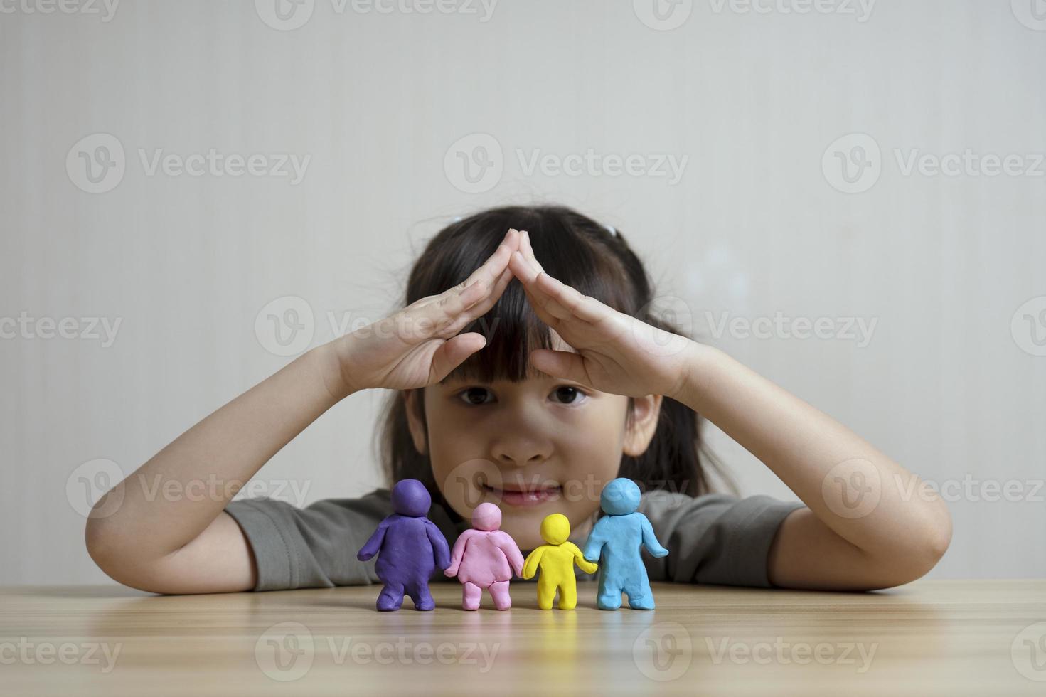 linda garota asiática constrói uma figura de plasticina de mãe, pai, filho e irmão. conceito de casa familiar e relacionamentos familiares. calor familiar e amor. criatividade e aprendizado das crianças foto