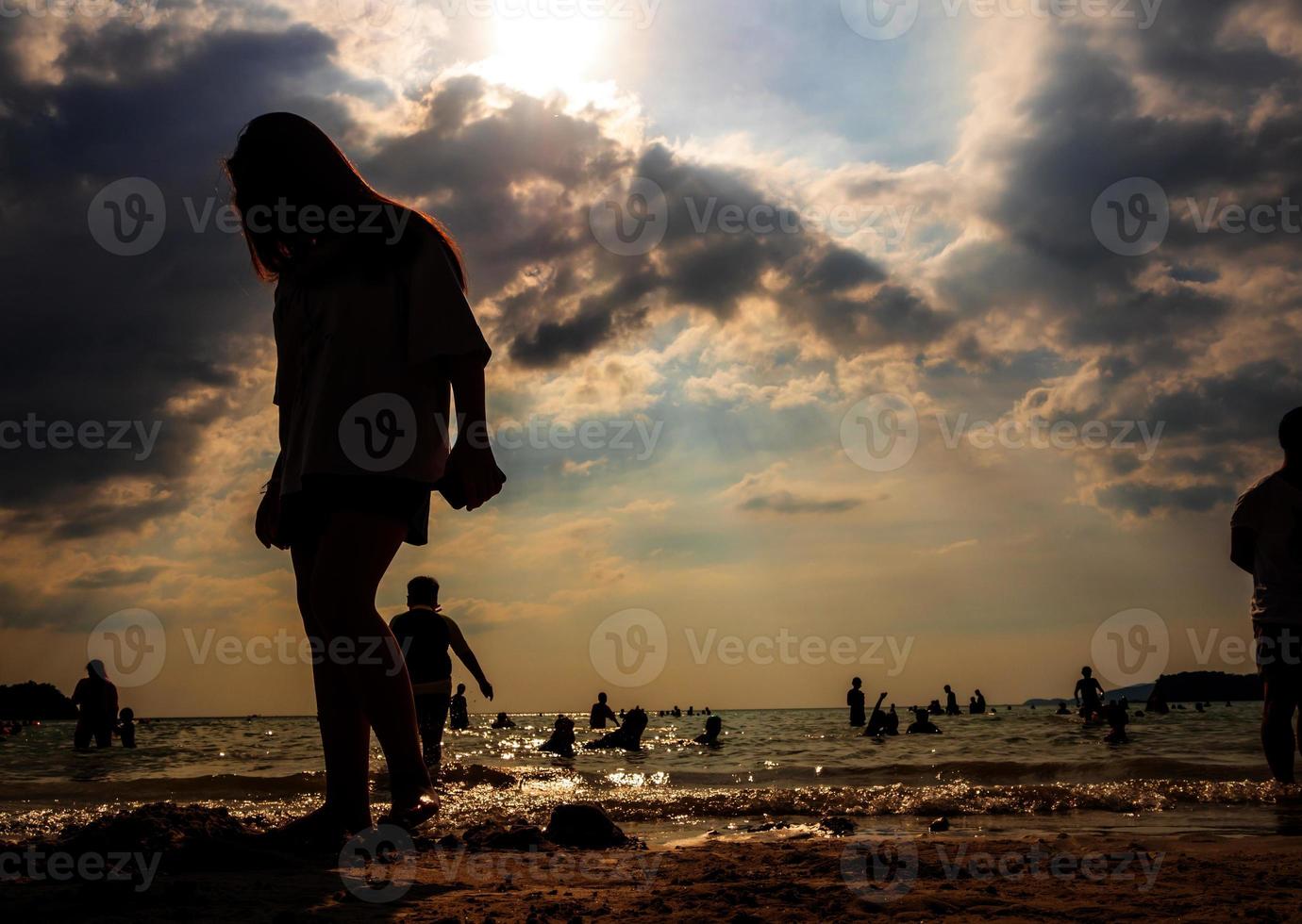 silhuetas de pessoas brincando no mar em uma praia pública foto