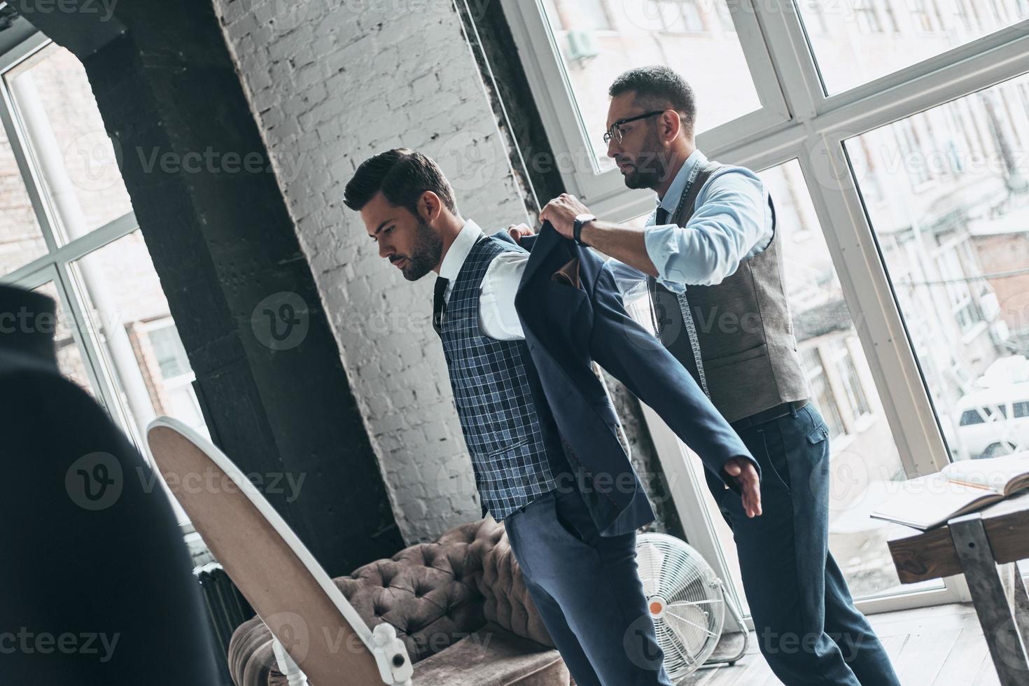 dois jovens elegantes medindo jaquetas foto