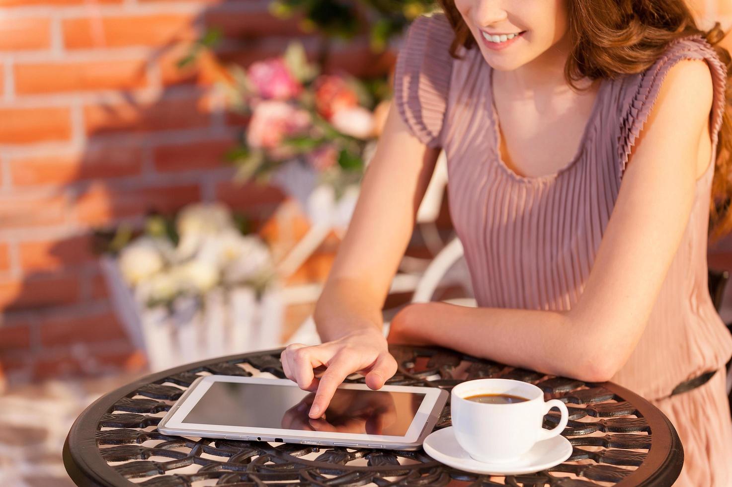 usando seu novo tablet no café. imagem recortada de mulher trabalhando em tablet digital enquanto está sentado no café ao ar livre foto