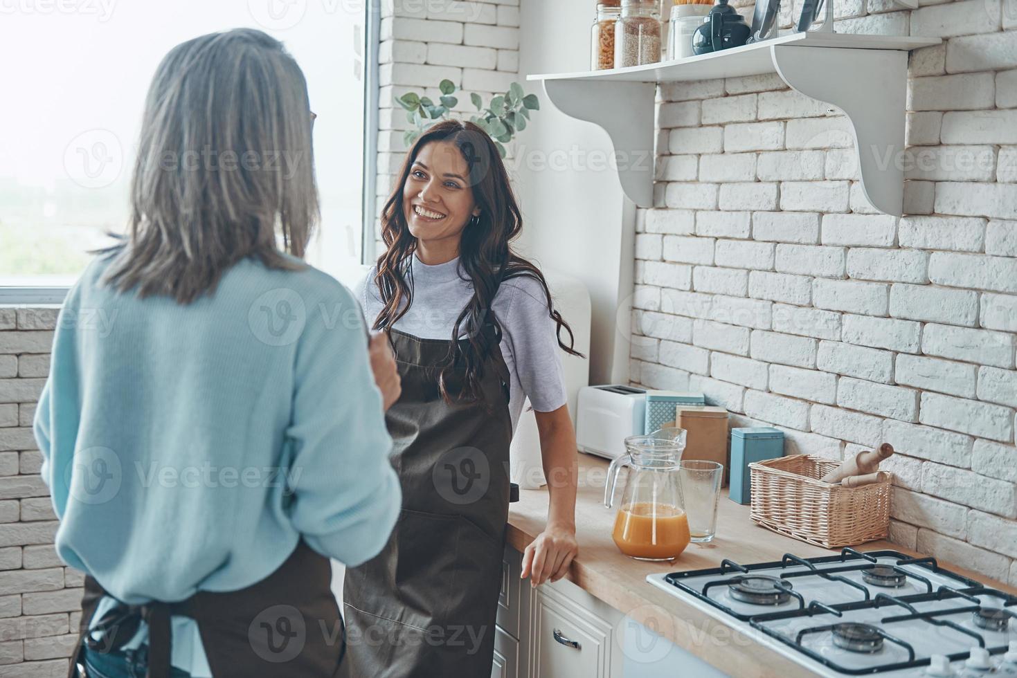 bela jovem e sua mãe se comunicando enquanto passa o tempo na cozinha doméstica foto