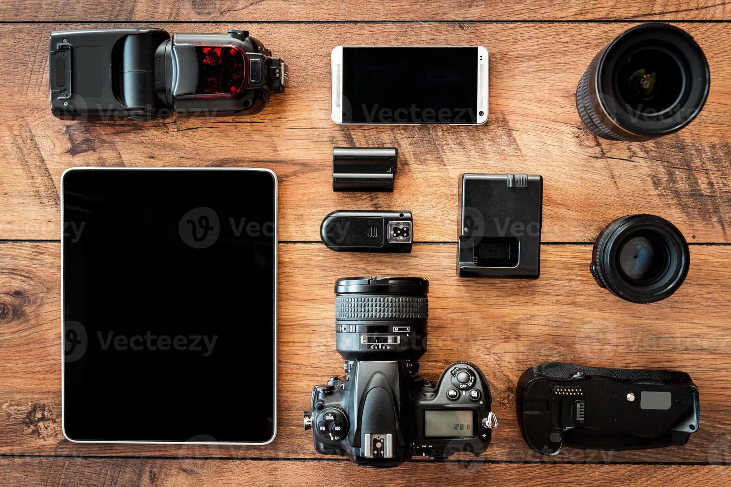 equipamento fotográfico. vista superior de diversos equipamentos pessoais para fotógrafo deitado no grão de madeira foto