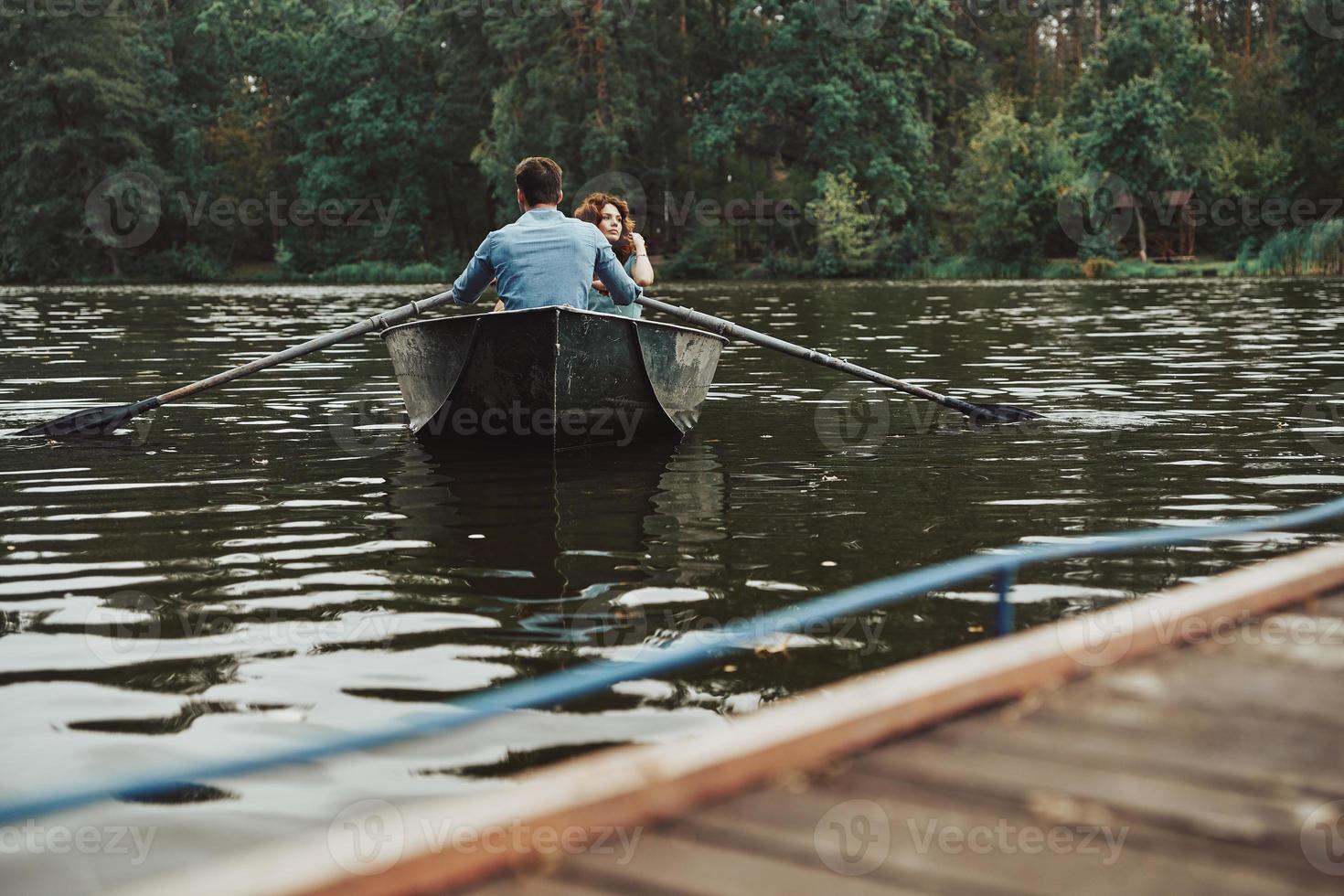 longe da cidade. lindo casal jovem desfrutando de um encontro romântico enquanto remava um barco foto