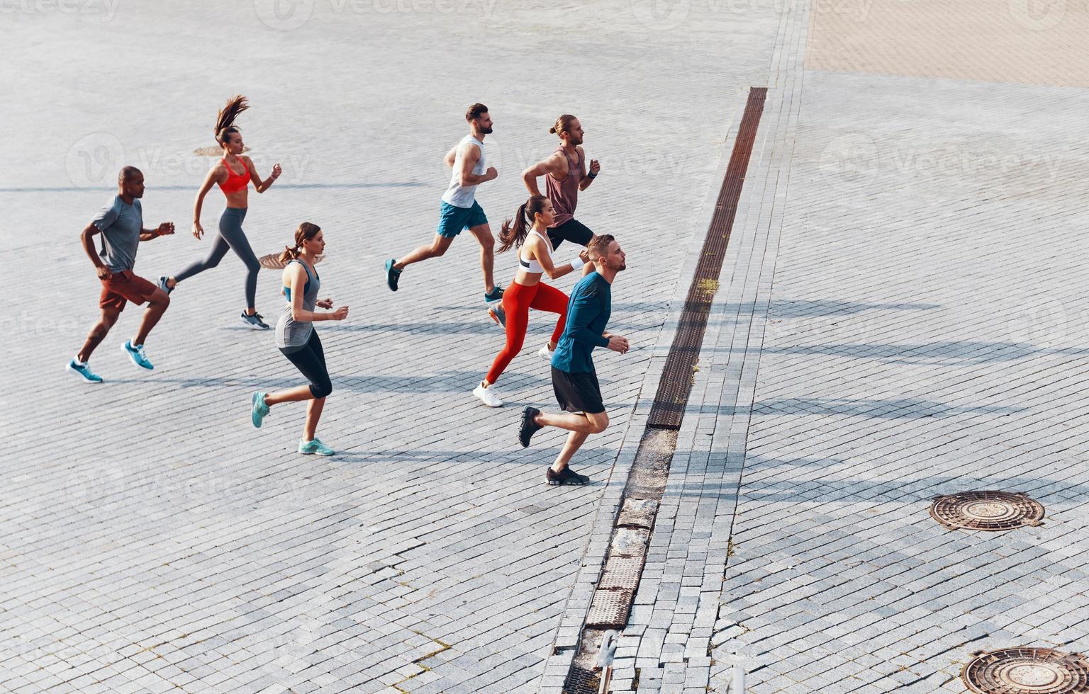 vista superior de corpo inteiro de jovens em roupas esportivas correndo durante o exercício ao ar livre foto