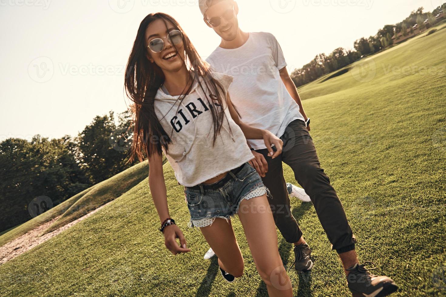 feliz por estar por perto. lindo casal jovem em roupas casuais sorrindo enquanto caminhava ao ar livre foto