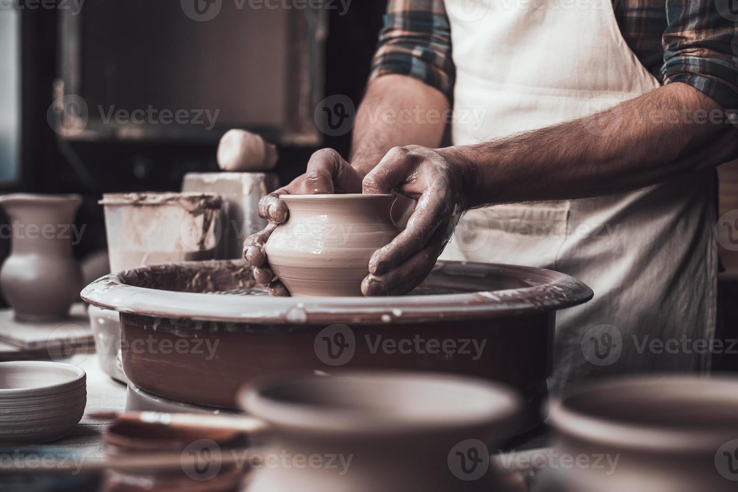 trabalho criativo. close-up de homem fazendo pote de cerâmica na roda de oleiro foto