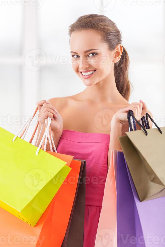 bom dia para compras. bela jovem de vestido rosa segurando sacolas de compras e sorrindo para a câmera foto