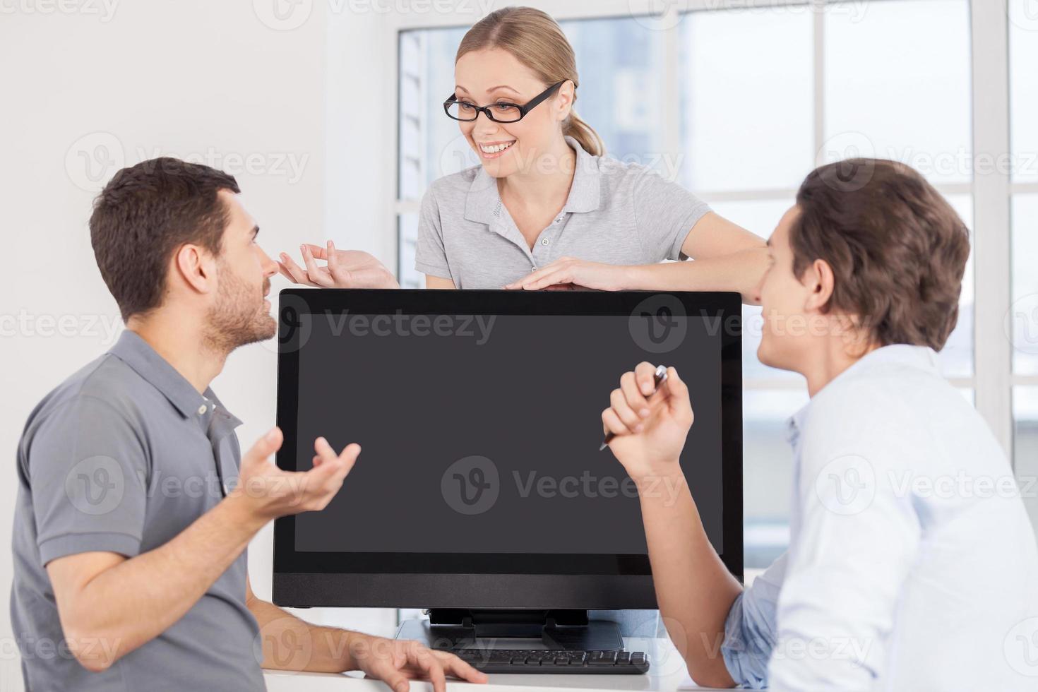 momentos de trabalho. três jovens alegres conversando entre si e gesticulando enquanto estão sentados no local de trabalho foto