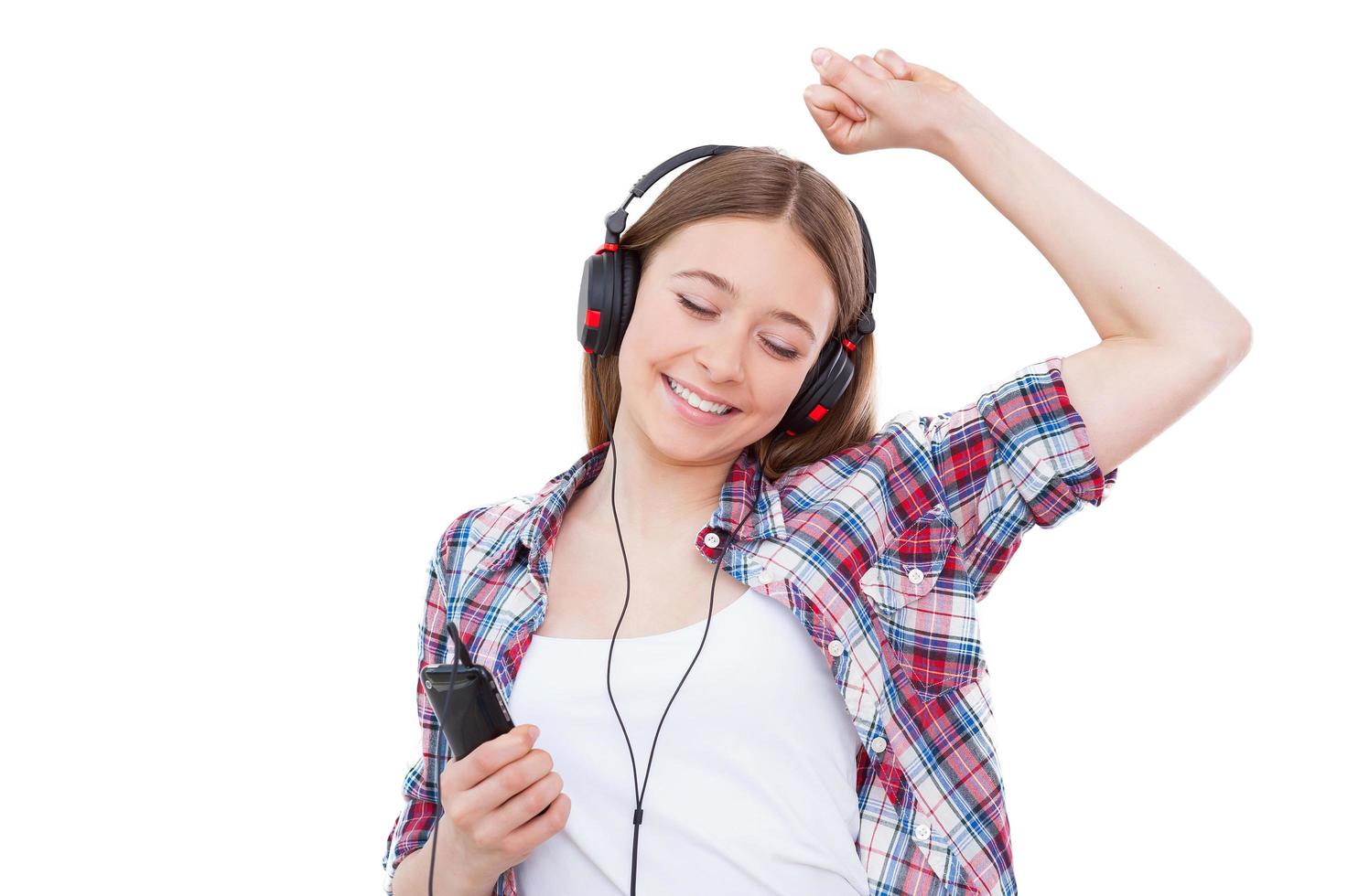 curtindo sua música favorita. linda adolescente em fones de ouvido, ouvindo a música e dançando em pé isolado no branco foto