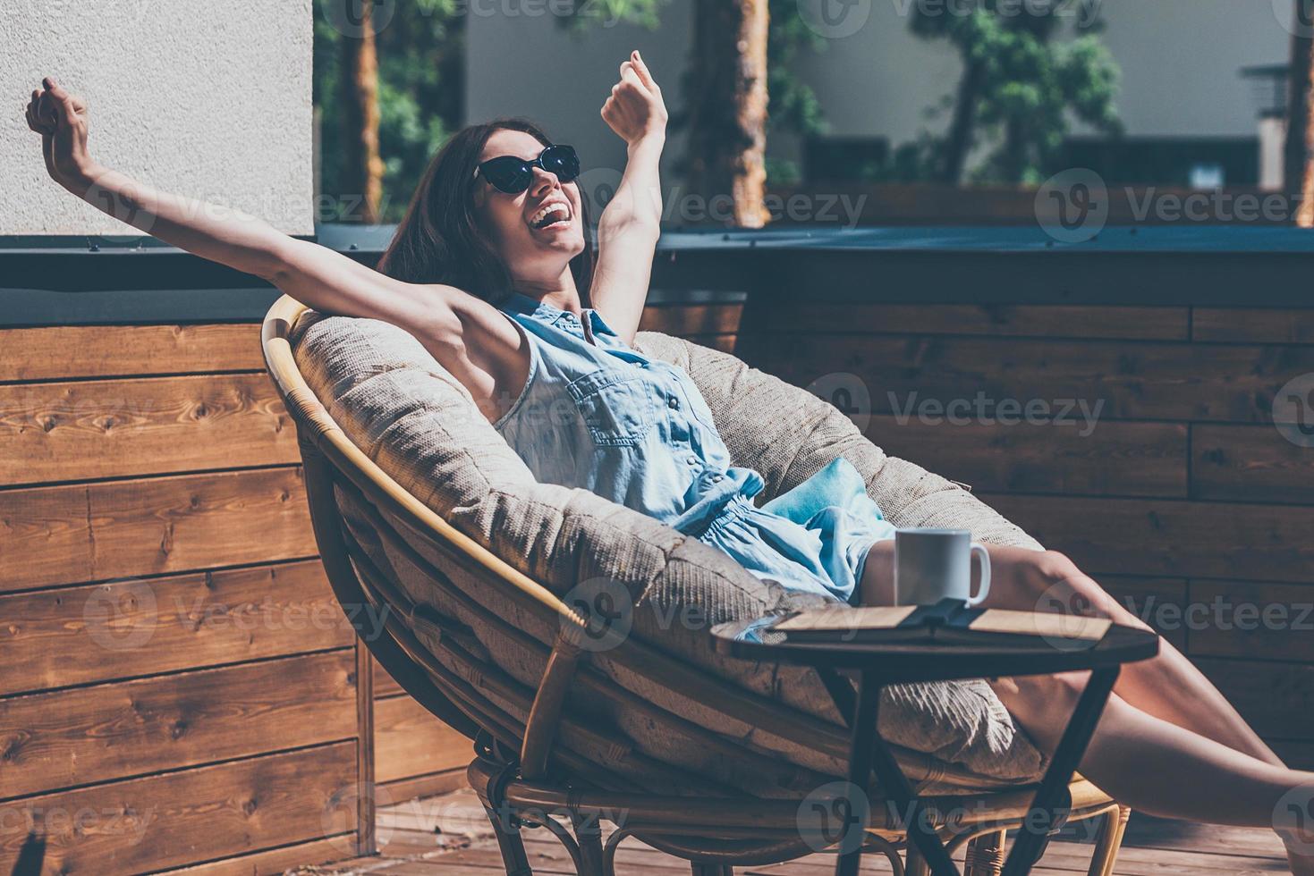 que lindo dia linda jovem relaxando em uma grande cadeira confortável no terraço de sua casa ao ar livre foto