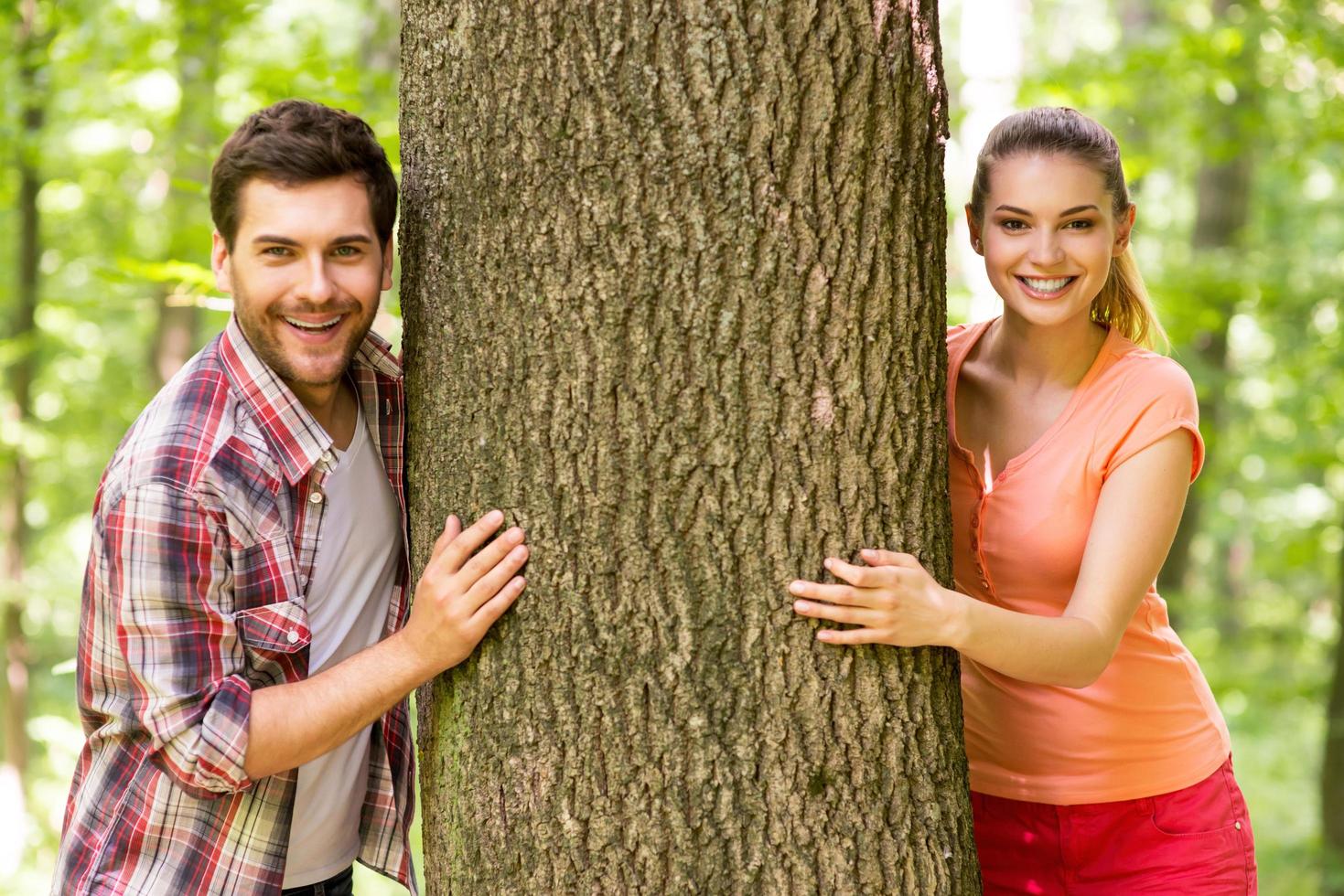 casal na natureza. lindo jovem casal apaixonado olhando para fora da árvore e sorrindo em pé em um parque foto