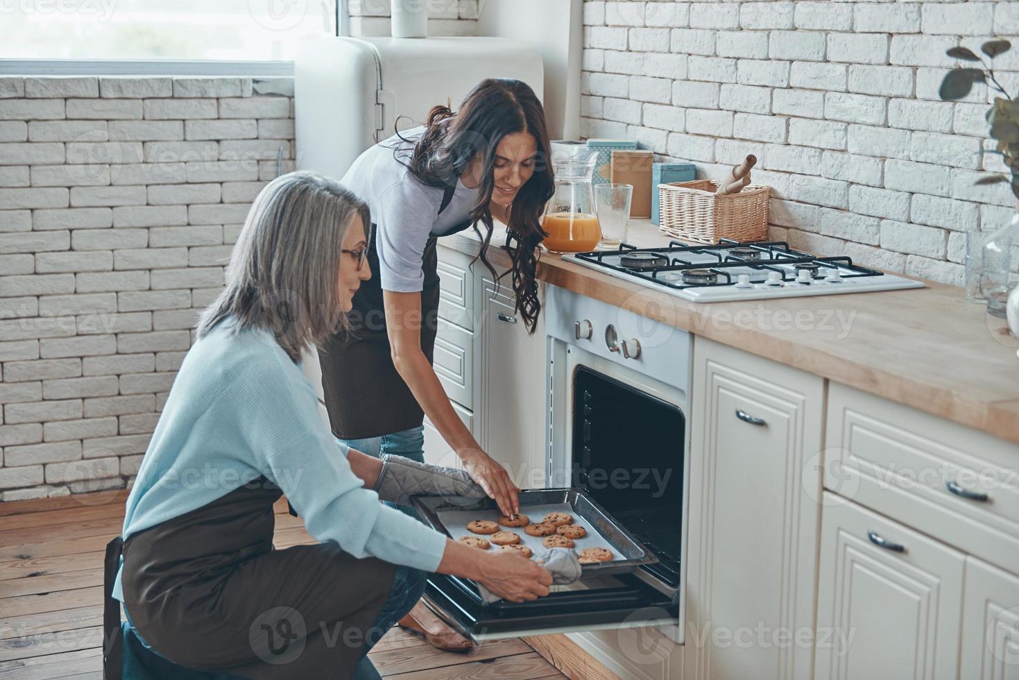 bela jovem e sua mãe cozinhando juntos enquanto passam o tempo na cozinha doméstica foto