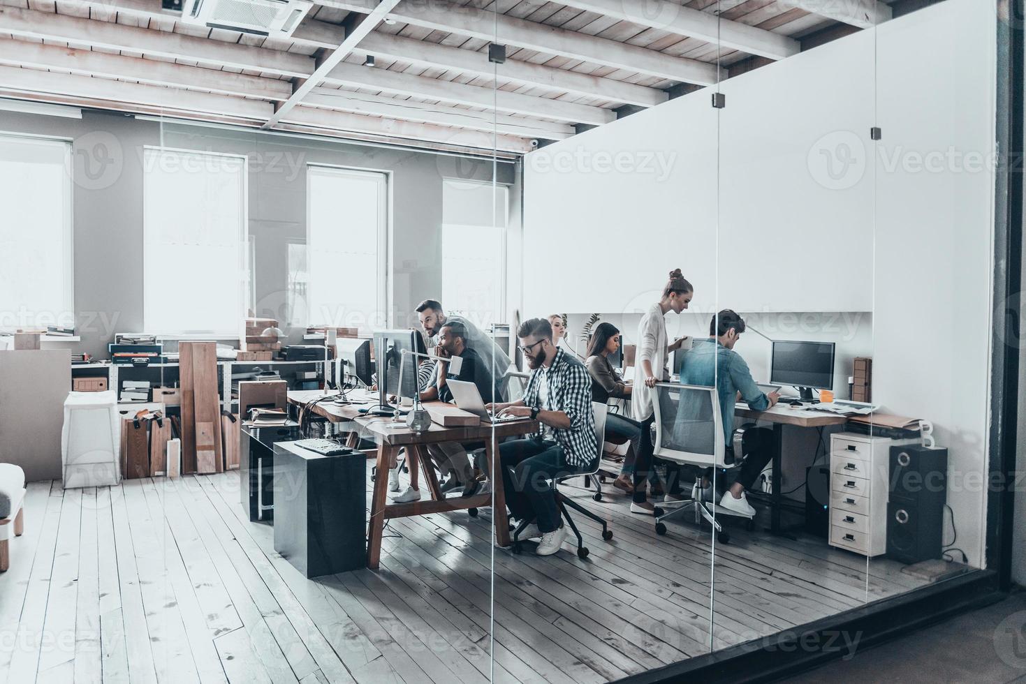 equipe de negócios de sucesso. grupo de jovens empresários trabalhando e se comunicando juntos enquanto estão sentados em seus locais de trabalho no escritório foto