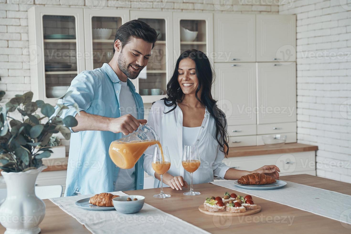 jovem casal despreocupado preparando o café da manhã juntos enquanto passa o tempo na cozinha doméstica foto