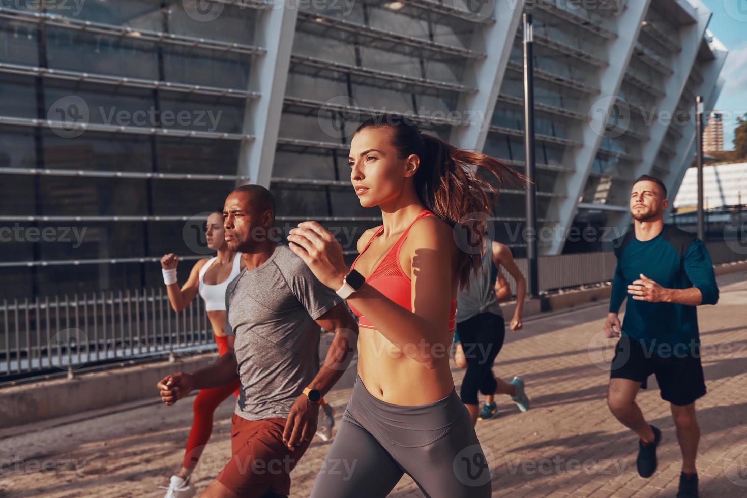 grupo de jovens em roupas esportivas correndo juntos ao ar livre foto