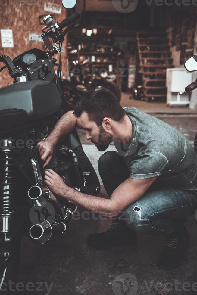 trabalhando em sua garagem. jovem confiante reparando moto perto de sua garagem foto