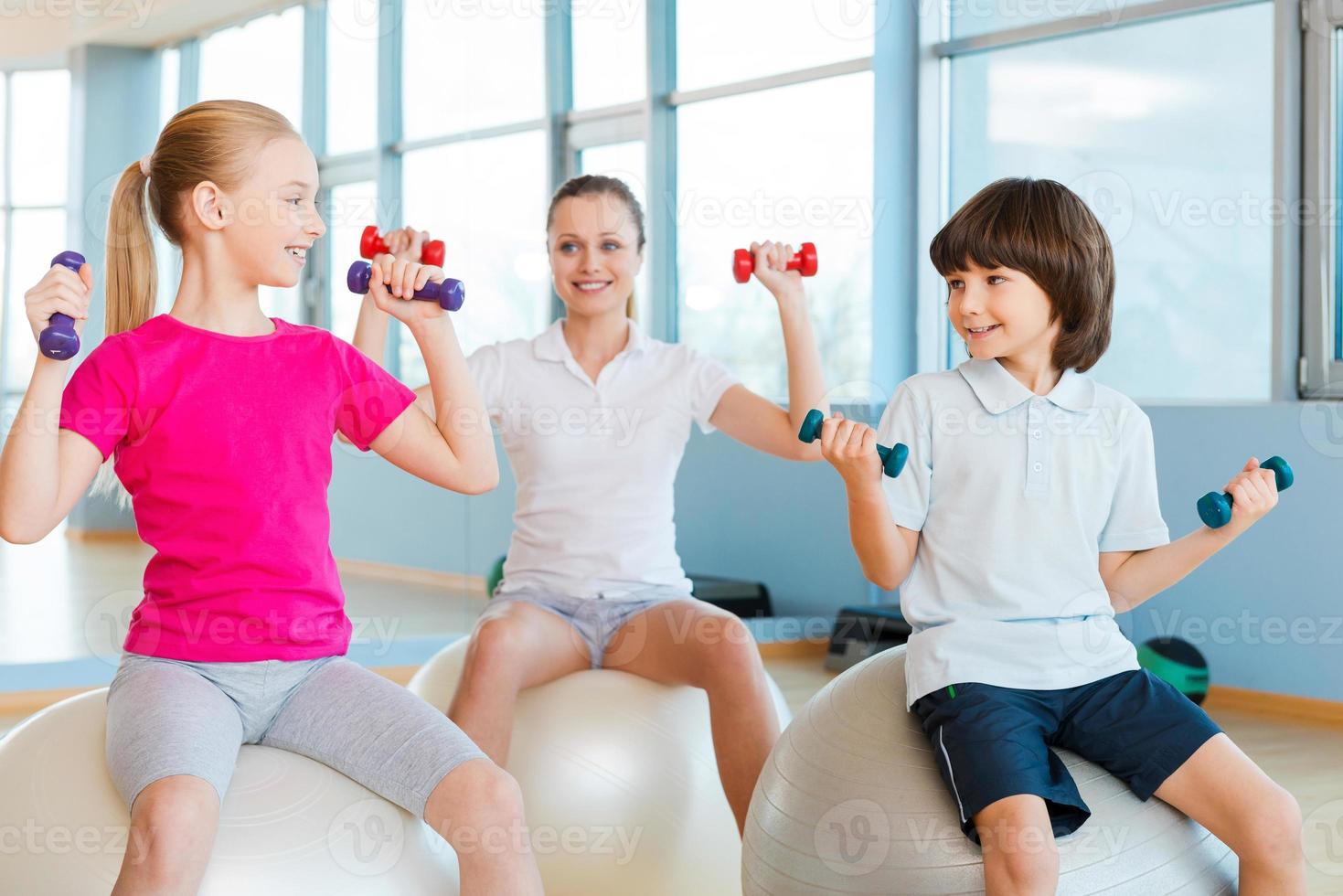 vivendo uma vida saudável. mãe e dois filhos se exercitando no health club e sorrindo foto