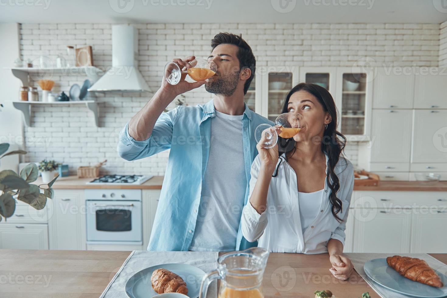 lindo casal jovem tomando café da manhã juntos enquanto passa o tempo na cozinha doméstica foto