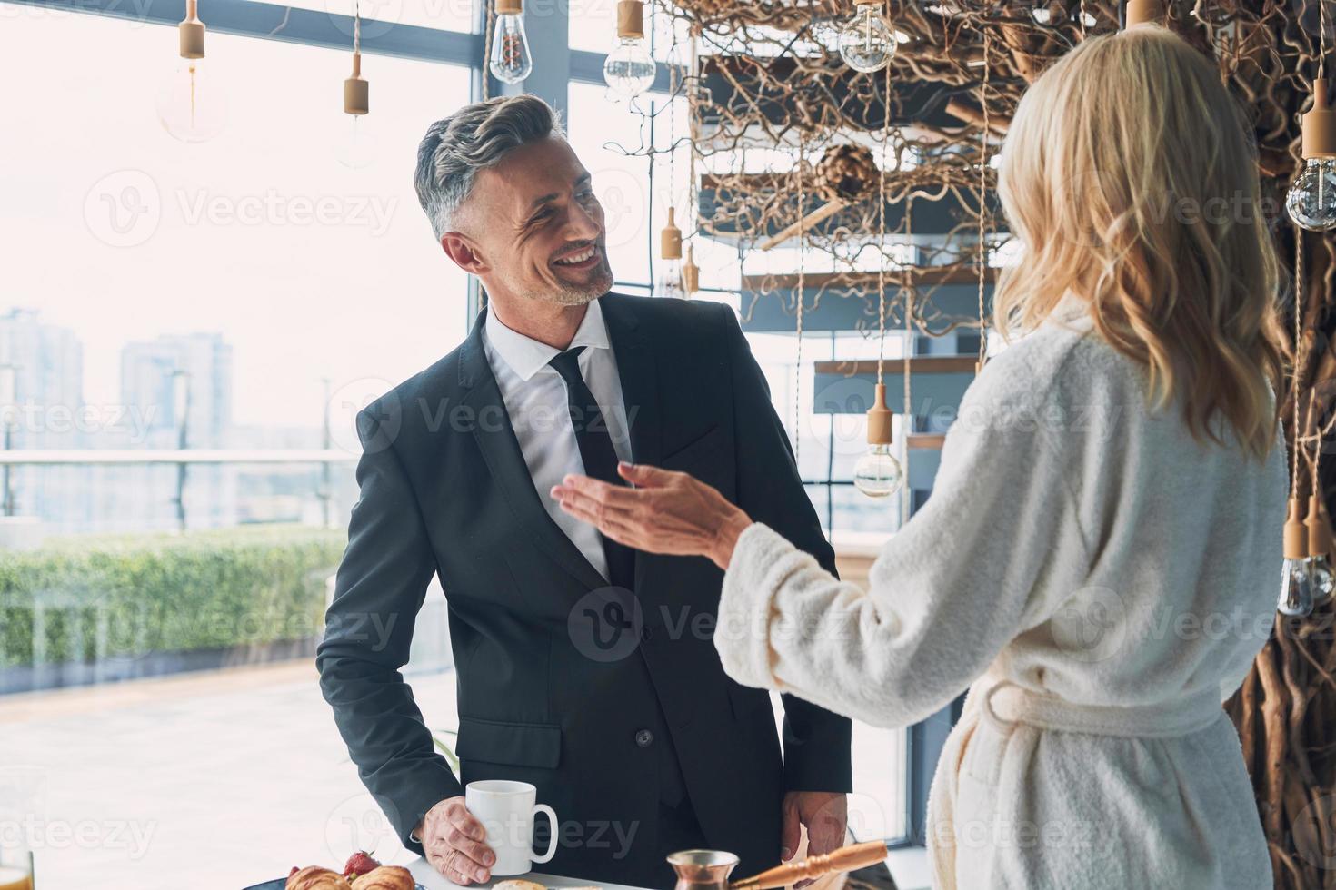 lindo casal maduro tomando café da manhã juntos enquanto passa o tempo na cozinha doméstica foto