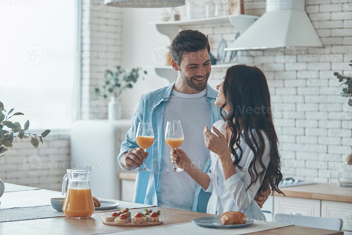 lindo casal jovem tomando café da manhã juntos enquanto passa o tempo na cozinha doméstica foto